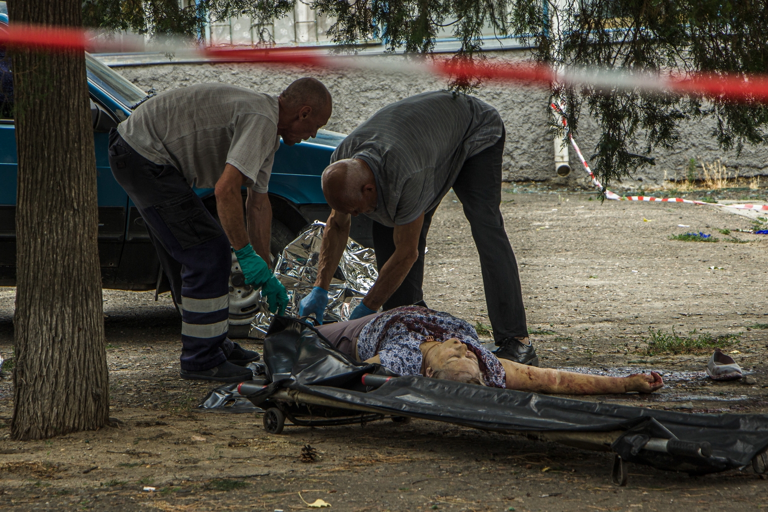 Volunteers cover the dead body of one of the victims of Russia's attack on Mykolaiv on July 29, 2022. (Mariia Horshkova/The Kyiv Independent)