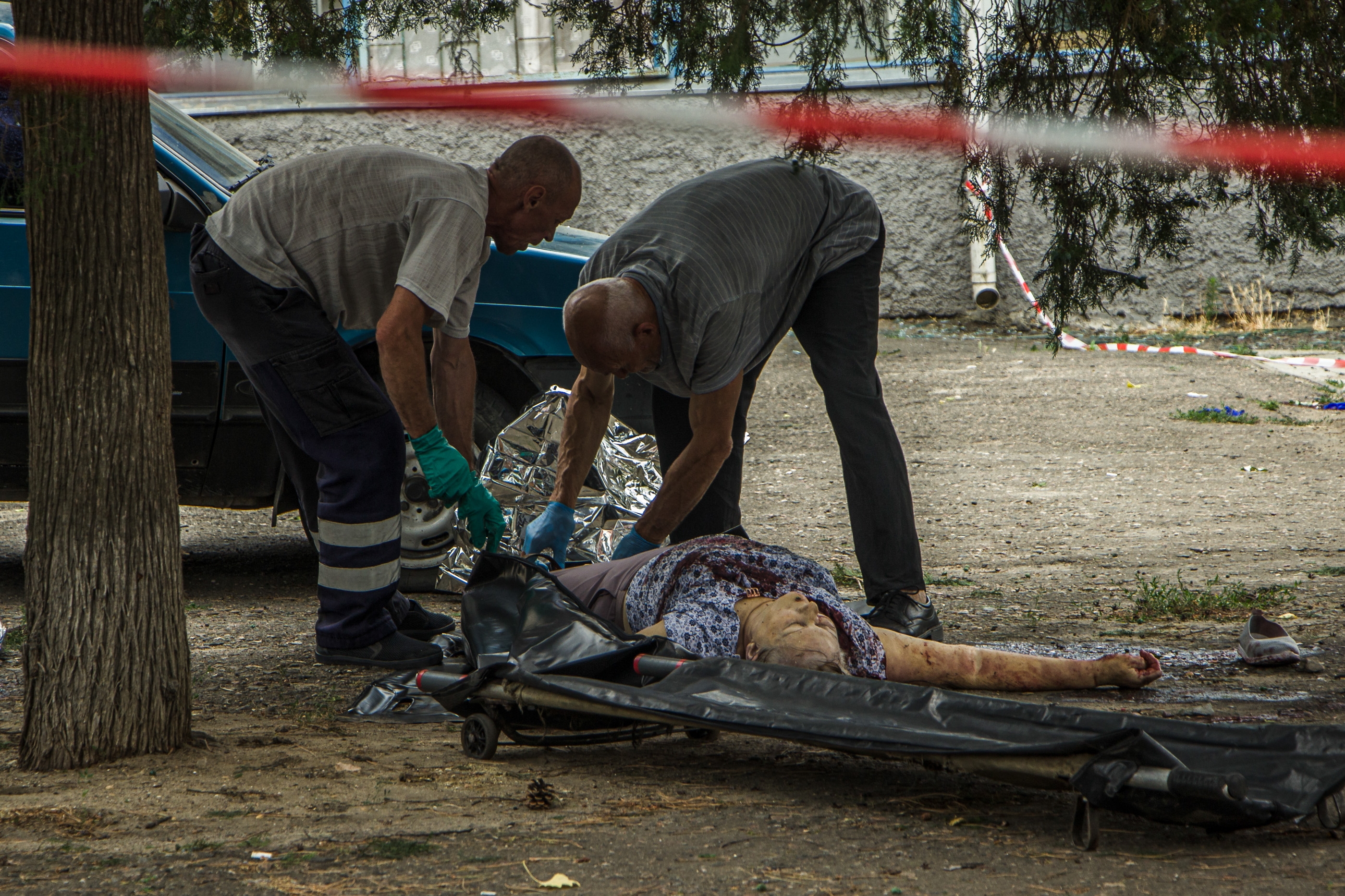Volunteers cover the dead body of one of the victims of Russia's attack on Mykolaiv on July 29, 2022. (Mariia Horshkova/The Kyiv Independent)