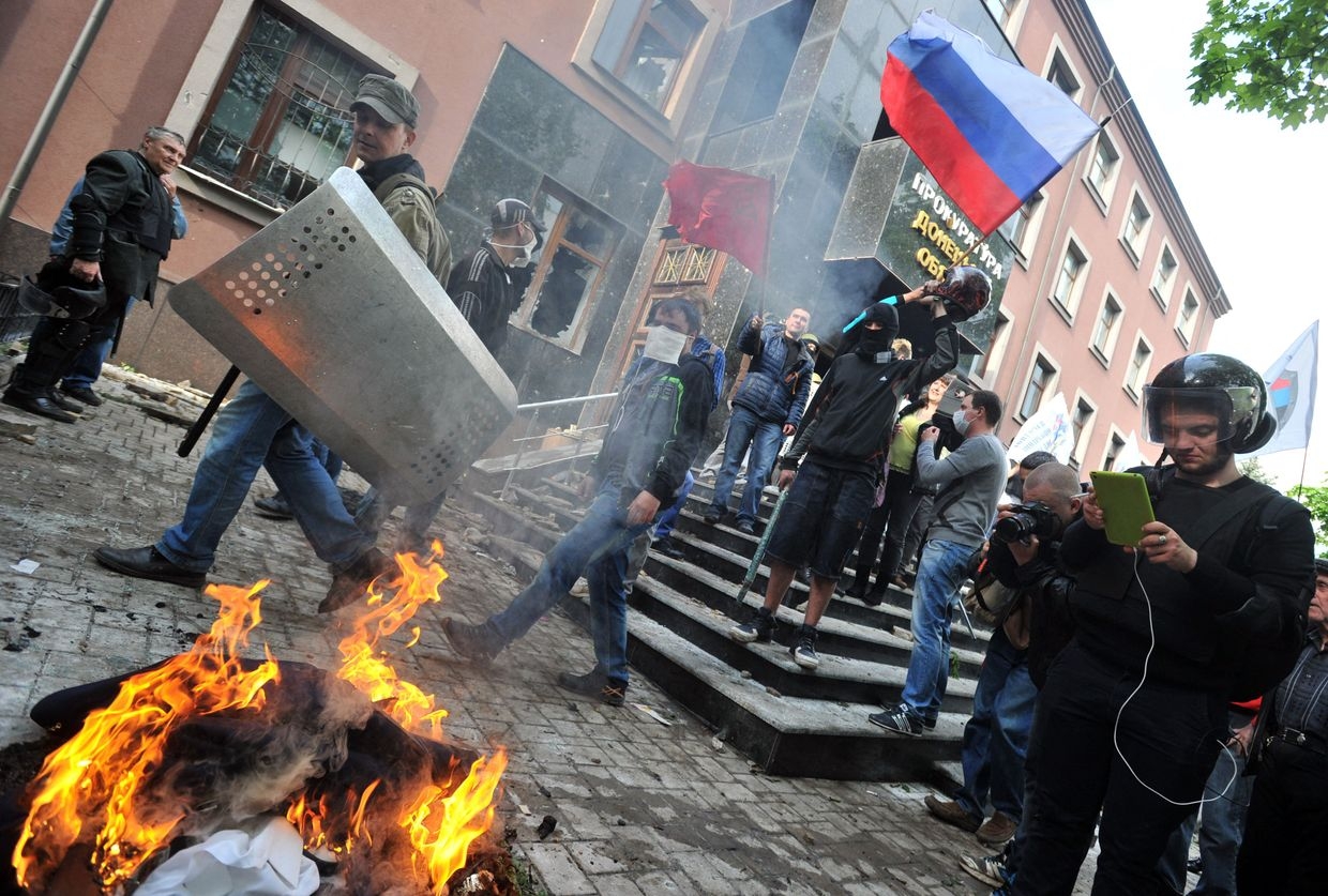 Portraits and uniforms of Ukrainian prosecutors burn outside the prosecutor's office as Russia-becked separatists attempt to capture Donetsk
