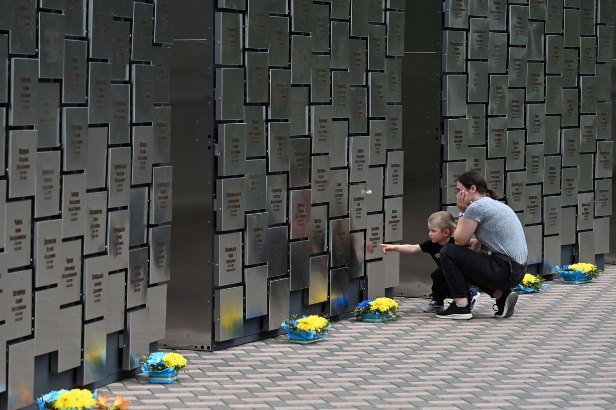 A young woman reacts as she stands with her son in front of a recently inaugurated memorial, including 501 plates bearing 