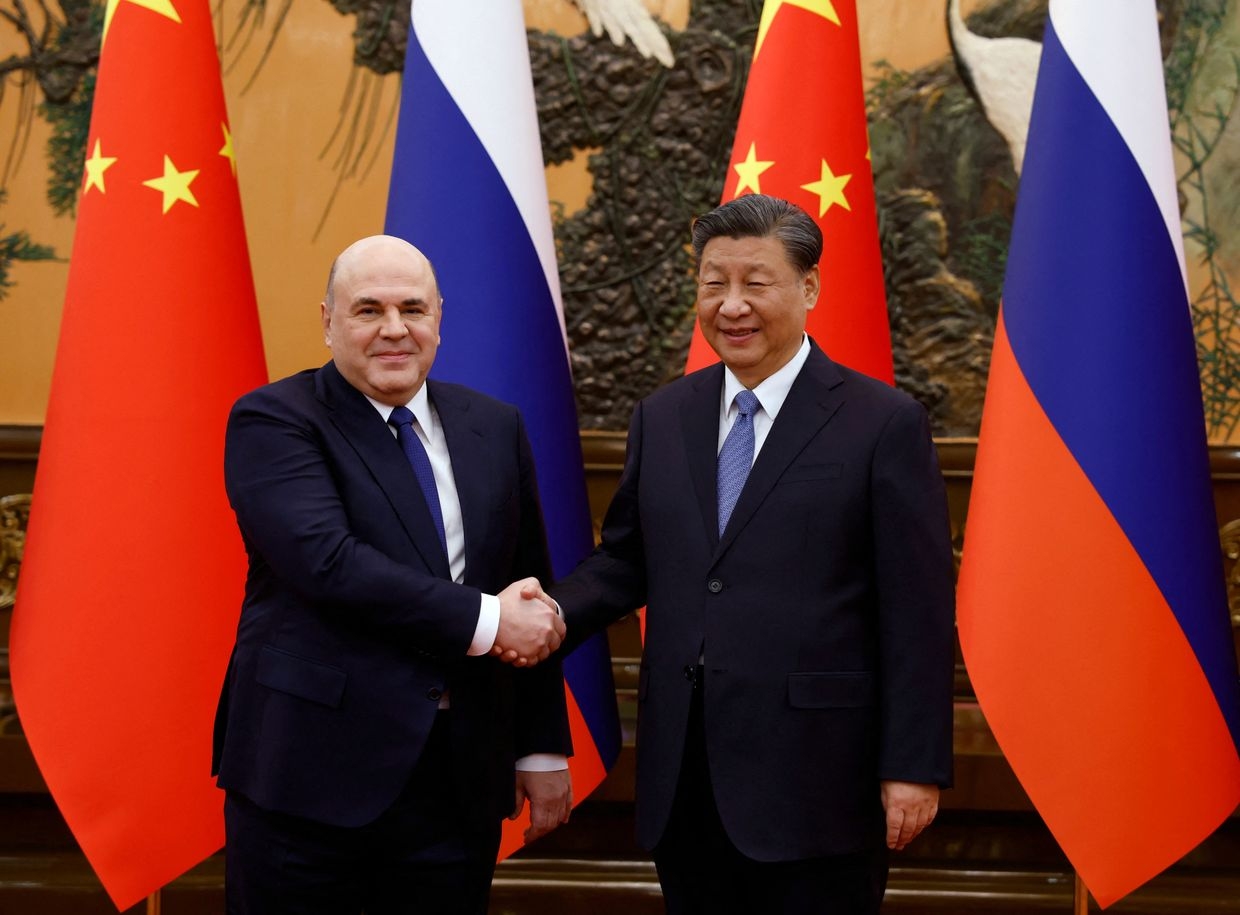 This pool photograph distributed by Russian state-owned agency Sputnik shows Russian Prime Minister Mikhail Mishustin and Chinese President Xi Jinping shaking hands