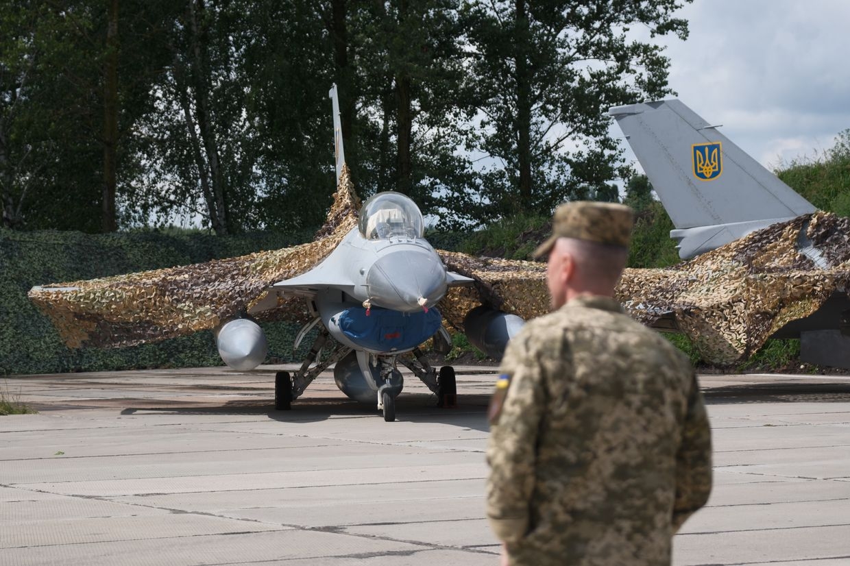 Ukrainian military member stands next to the first General Dynamics F-16 Fighting Falcon 