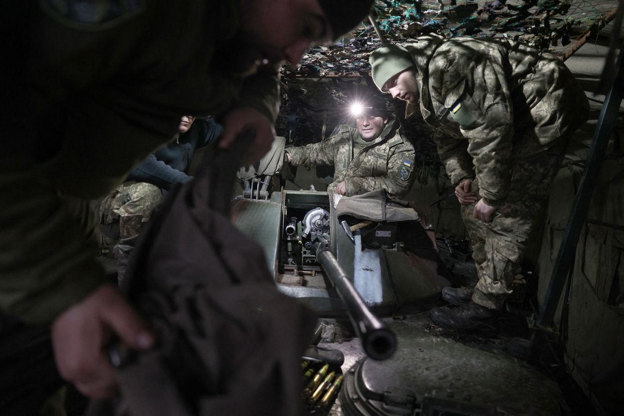 Ukrainian servicemen install an automatic cannon after preventive maintenance on an armored military vehicle at a workshop in the Donetsk Oblast, Ukraine