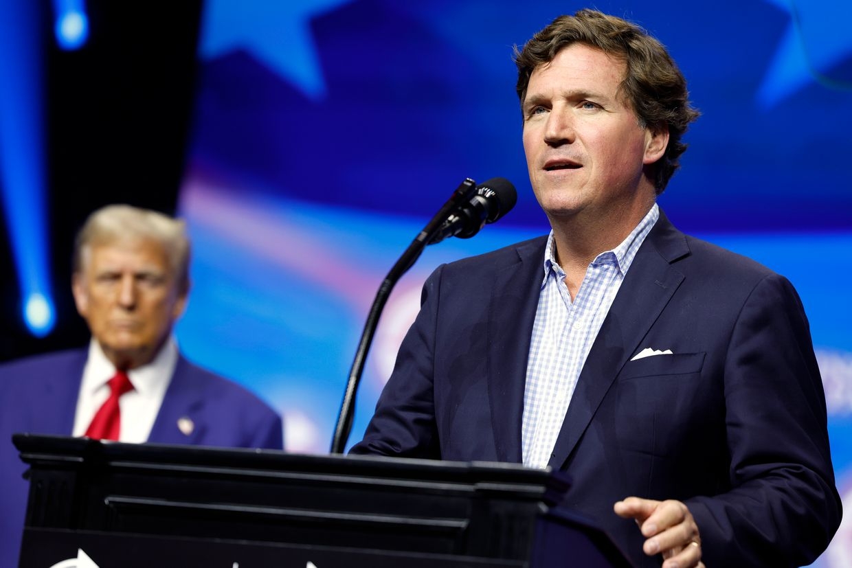 Political commentator Tucker Carlson speaks with Donald Trump during a Turning Point Action rally in Duluth, Georgia, U.S. on Oct. 23, 2024. 