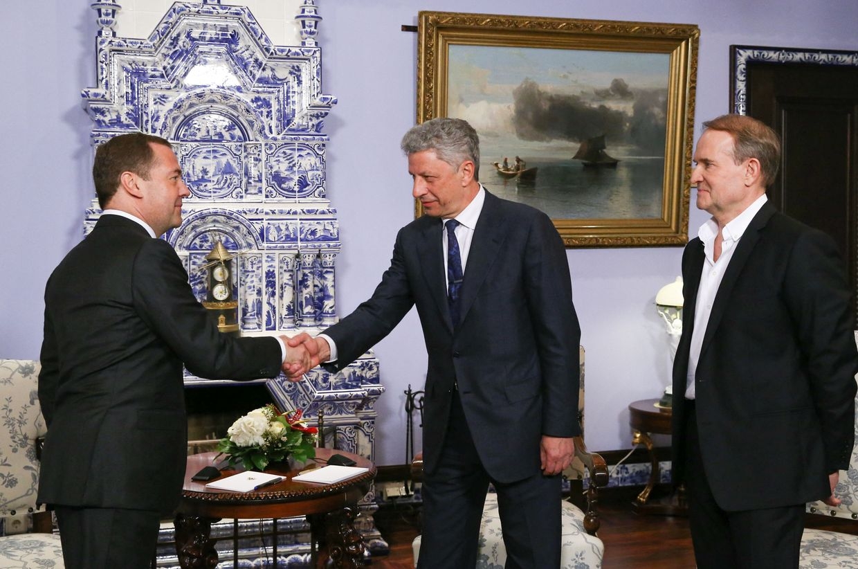 Russian ex-PM Dmitry Medvedev (L) shakes hands with former Ukrainian candidate Yuriy Boyko, with businessman Viktor Medvedchuk nearby, March 22, 2019.