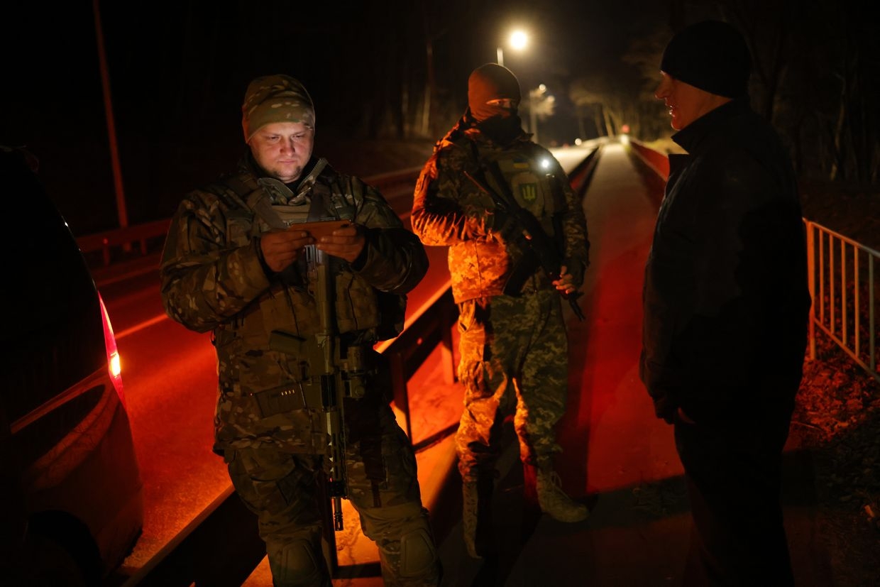 Yaroslav Kryvulya (L) checks ID of a man who broke curfew, leading paramilitary group TSEL in Lviv, Ukraine, on Feb. 23, 2023.