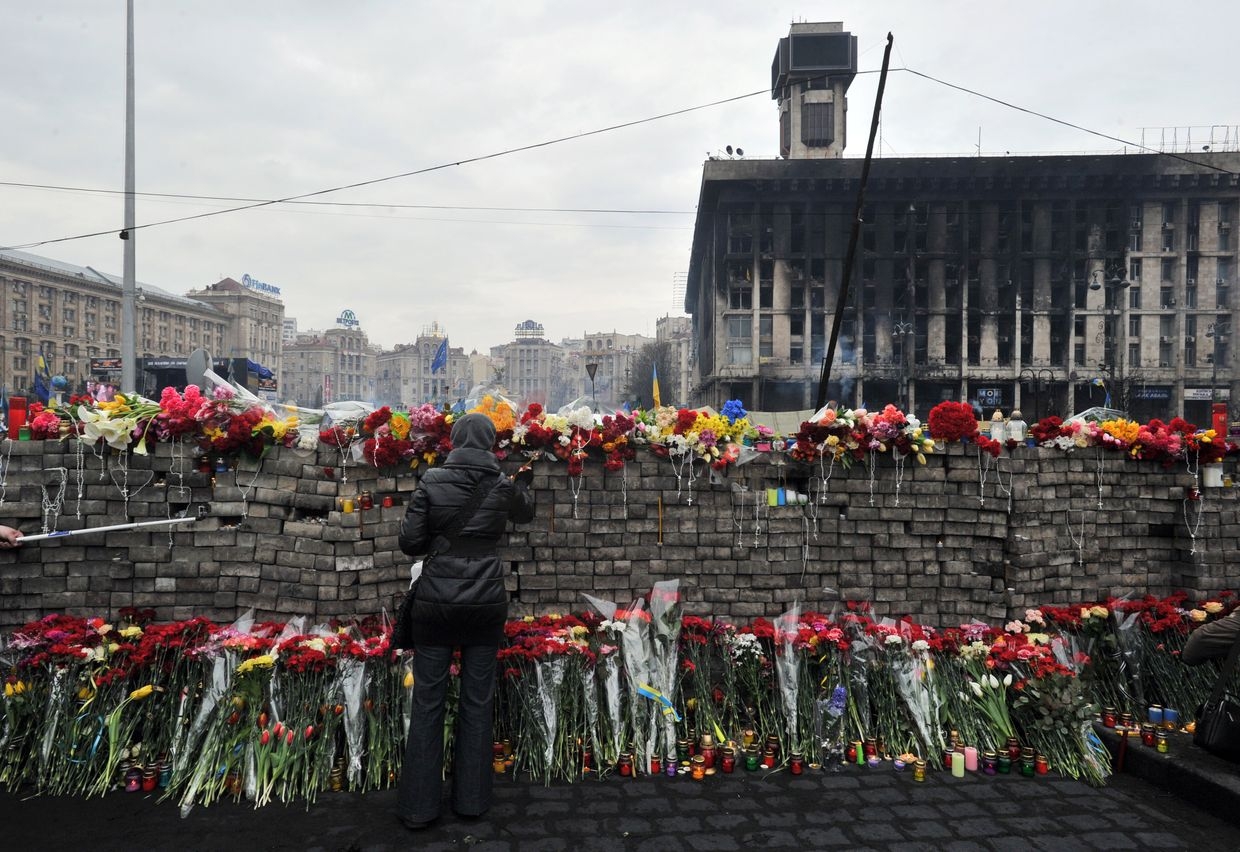 A woman sets a candle on a wall of bricks in memory of protesters killed during the Revolution of Dignity in Kyiv, Ukraine, on Feb. 23, 2014. 