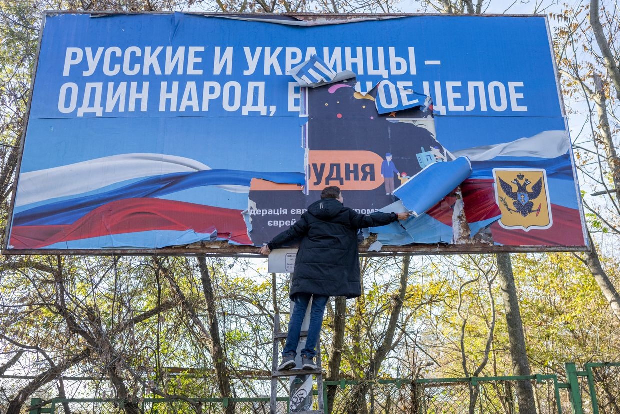 A man removes a Russian occupation banner in newly liberated Kherson, Ukraine, on Nov. 14, 2022. 