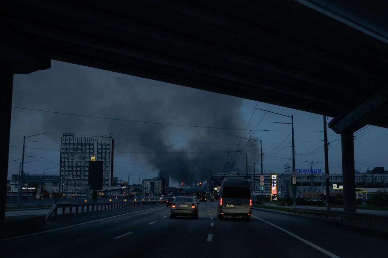 Cars drive on a road as smoke rises in the distance following a Russian missile attack in Kyiv, Ukraine, on April 6, 2025.