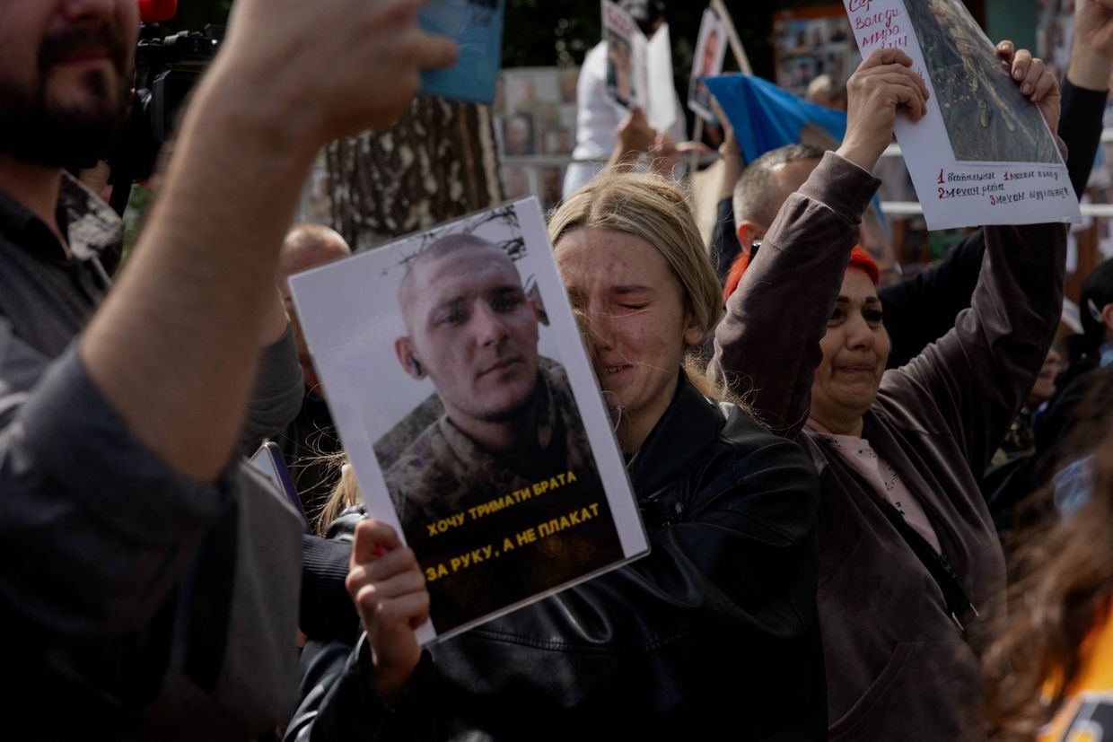 A girl cries while holding a photograph of her relative, a prisoner of war, during a POW exchange at an undisclosed location in Ukraine on June 12, 2025, amid the Russian invasion of Ukraine. 