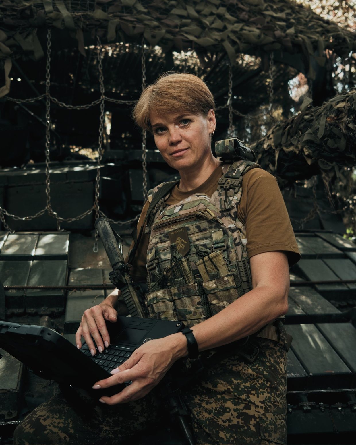 Vitalina, a soldier of Khartiia Brigade, restores communications inside a tank in an unspecified location, Ukraine, on an unspecified date. 