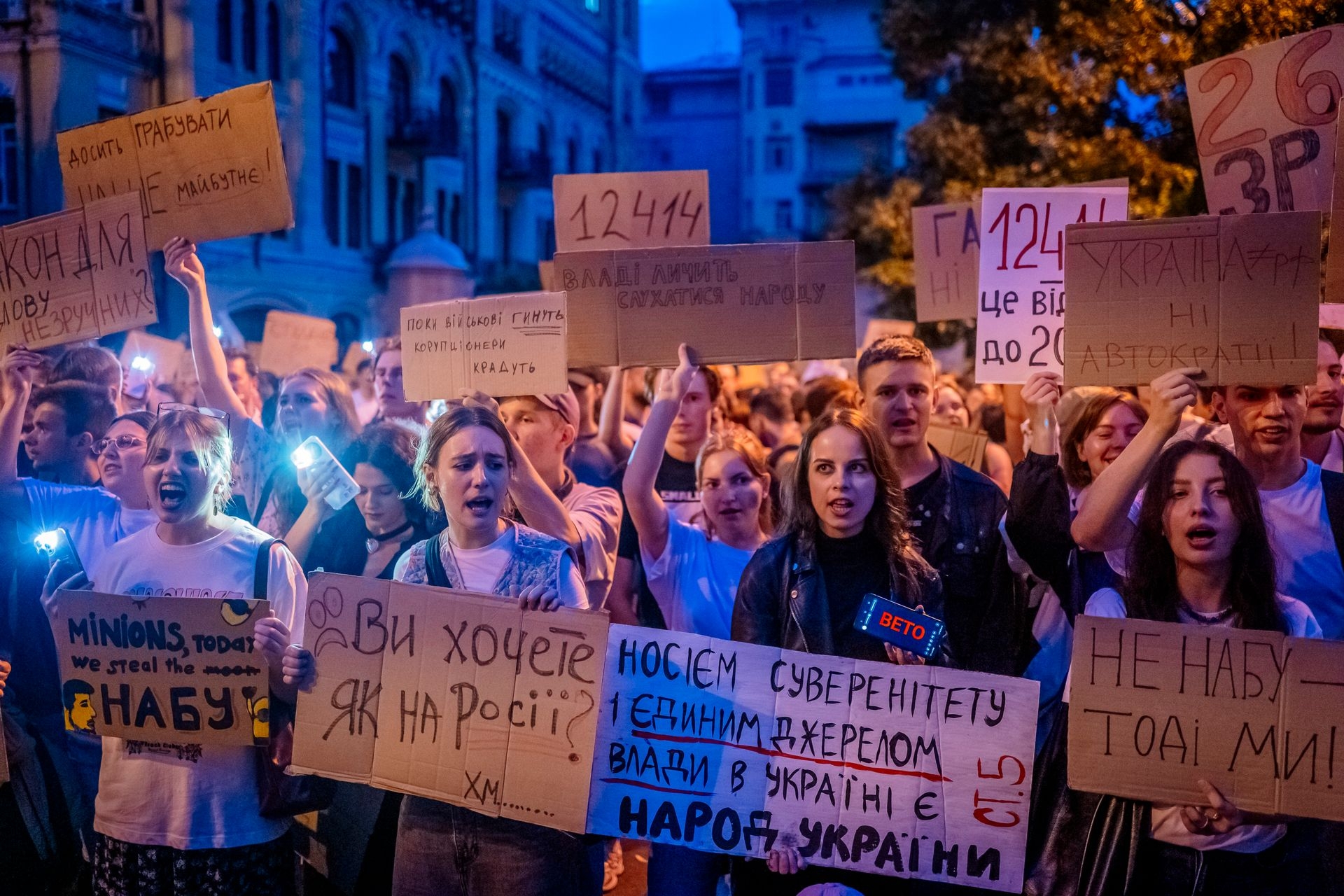 Protesters turn on flashlights and hold placards during a rally against a law restricting the independence of anti-corruption institutions in Kyiv, Ukraine, on July 22, 2025. 