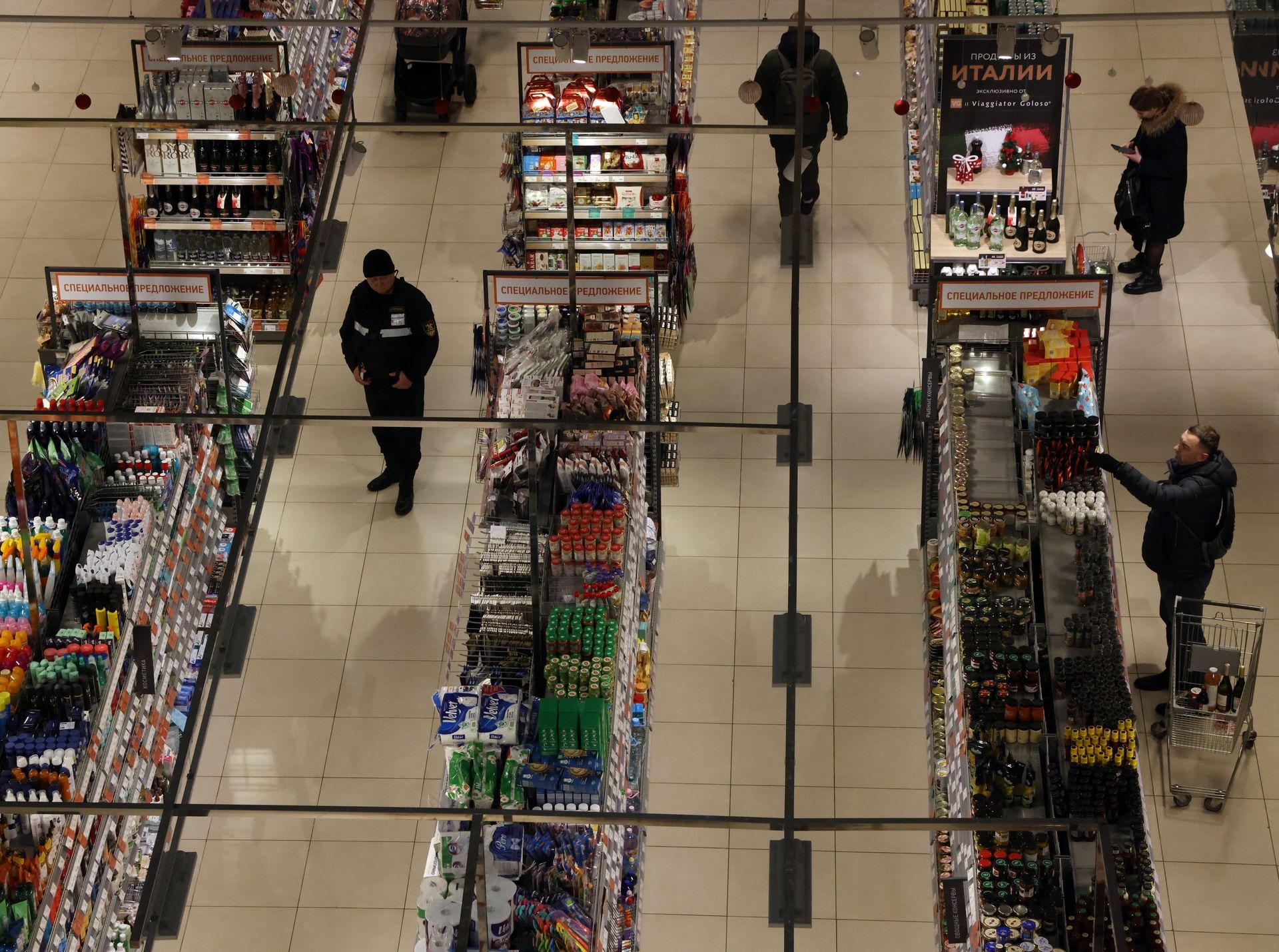 Shoppers and a security guard look at grocery shelves inside a Miratorg supermarket in Moscow, Russia, on Dec. 23, 2022.