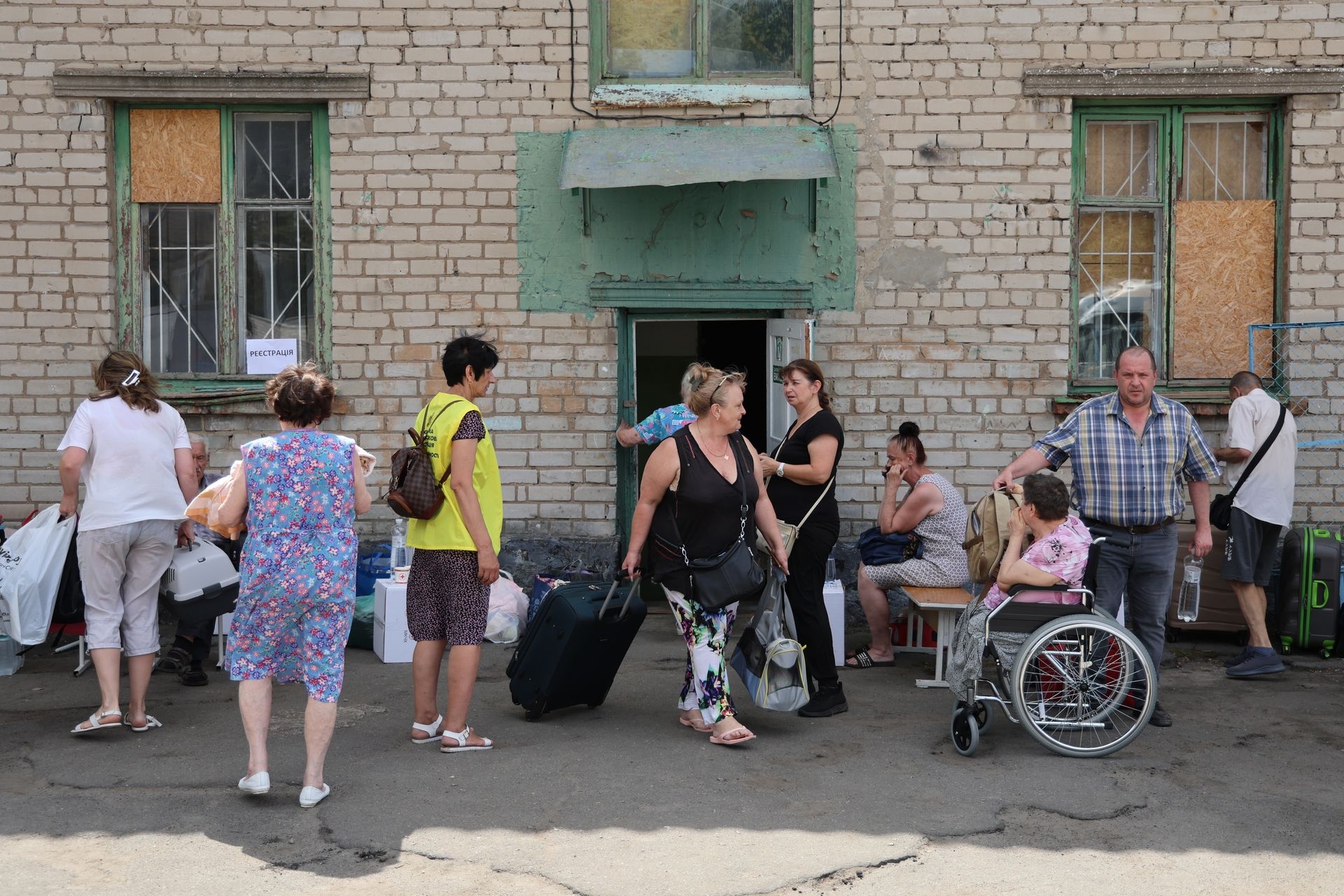 People with bags wait for registration during the evacuation in Kherson, Ukraine, on Aug. 4, 2025. 