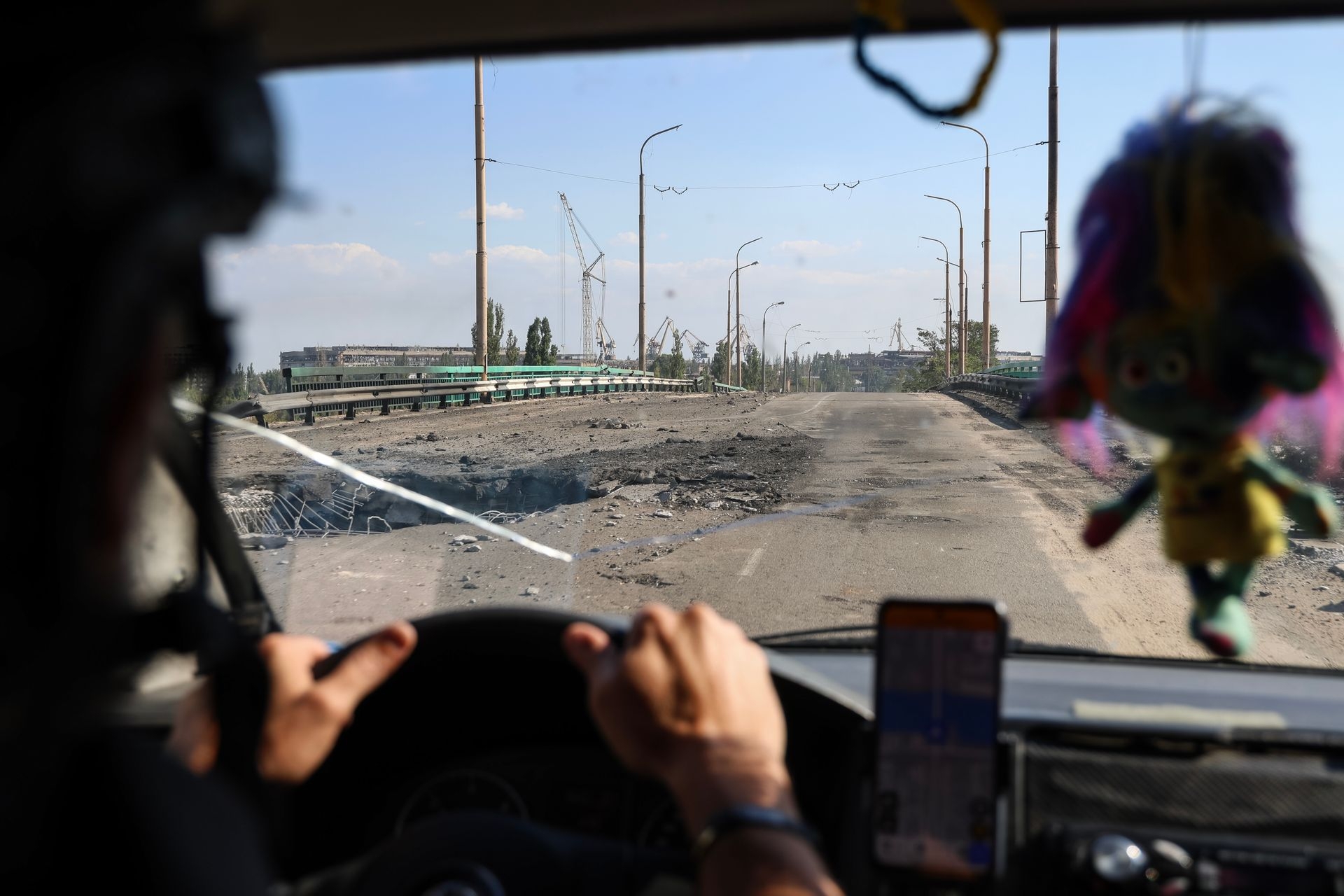 A car with volunteers drives over a damaged bridge after Russian airstrikes in Kherson, Ukraine, on Aug. 4, 2025.