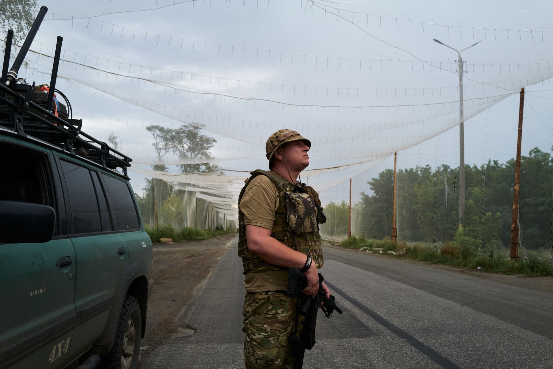 Ukrainian soldier scans for Russian FPV attack drones on a road partially shielded by anti-drone netting in Kostyantynivka, Ukraine, on Aug. 11, 2025.