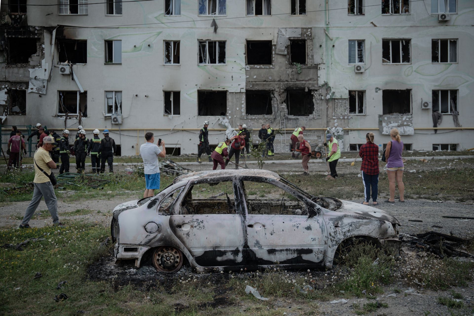 Ukrainian rescuers, city workers, and residents gather in front of a destroyed apartment building after a Russian drone attack in Kharkiv, Ukraine, on Aug. 18, 2025. 