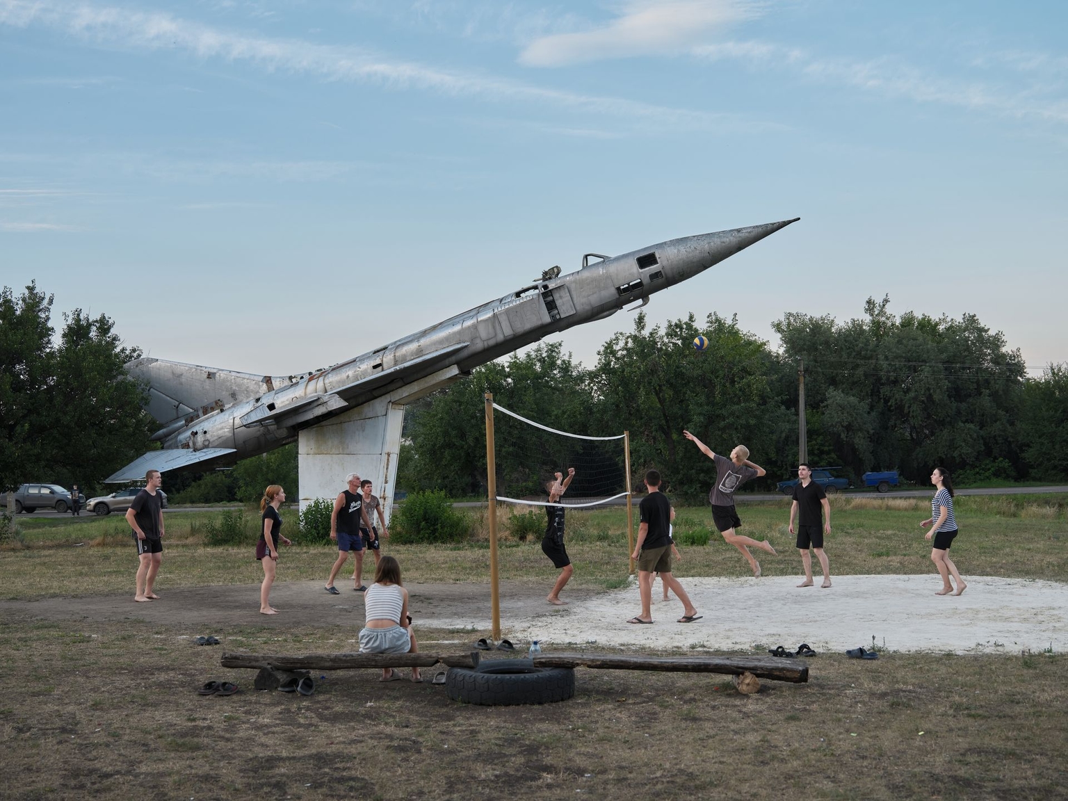 Children play volleyball near the combat zone next to a Soviet-era fighter jet monument in Donetsk Oblast, Ukraine, on July 21, 2025.