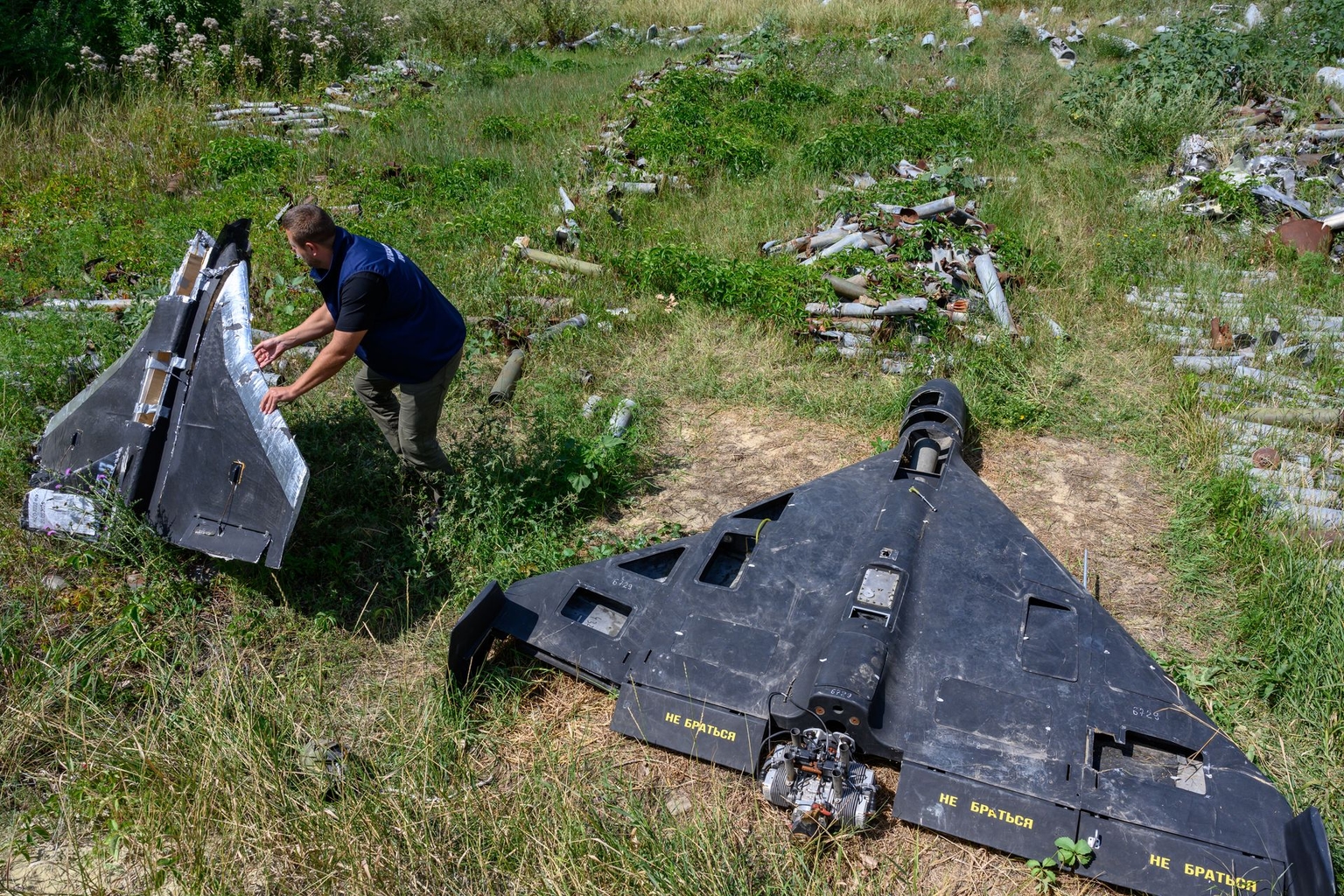 A person holds the remains of a Russian-made decoy drone, known as a Gerbera, beside an Iran-designed Shahed-136 drone, or Geran-2, in Kharkiv, Ukraine, on July 30, 2025.