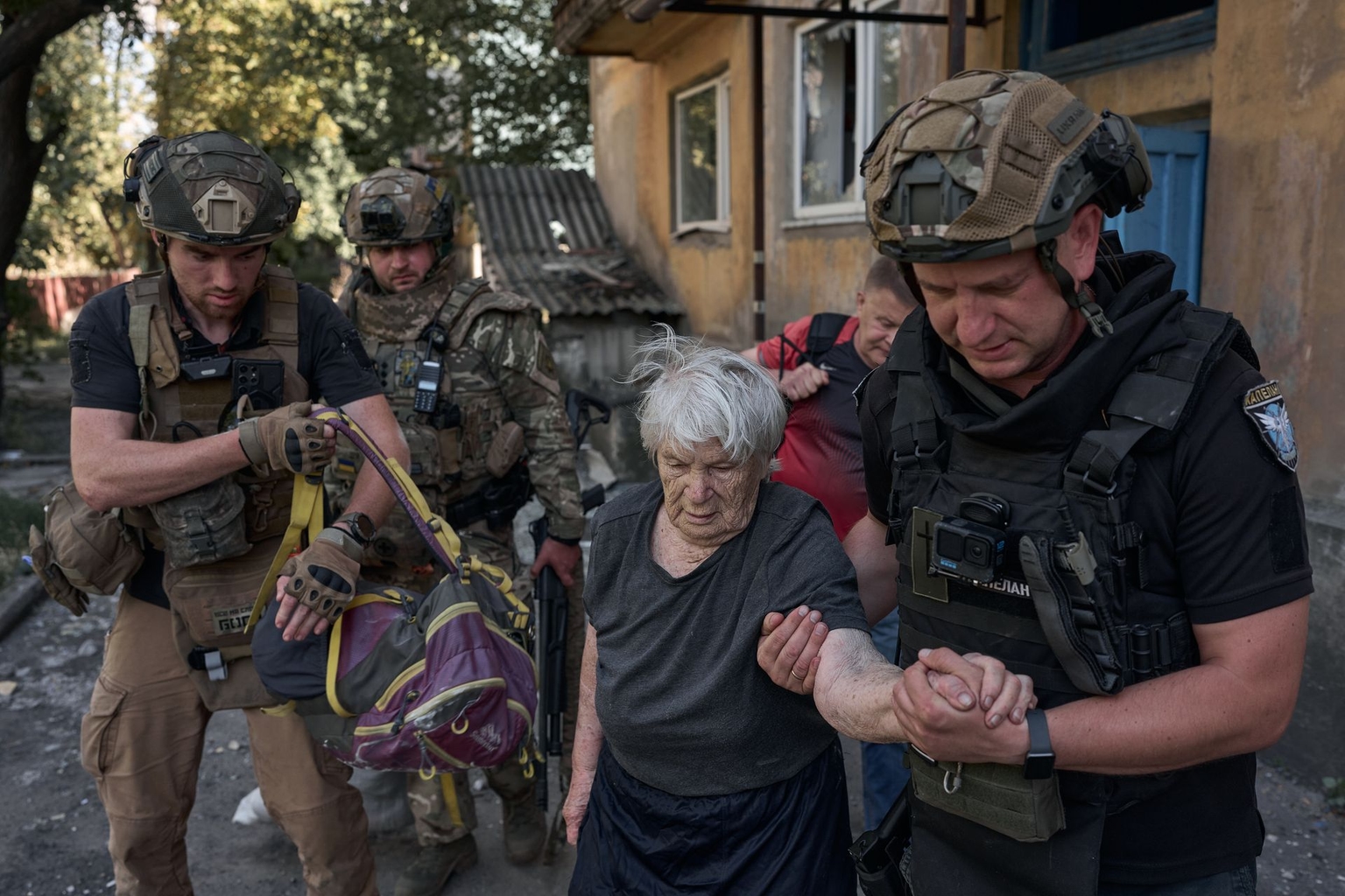 A woman is helped by volunteers as she is evacuated to a designated gathering point in Dobropillia, Donetsk Oblast, Ukraine, on Aug. 19, 2025.