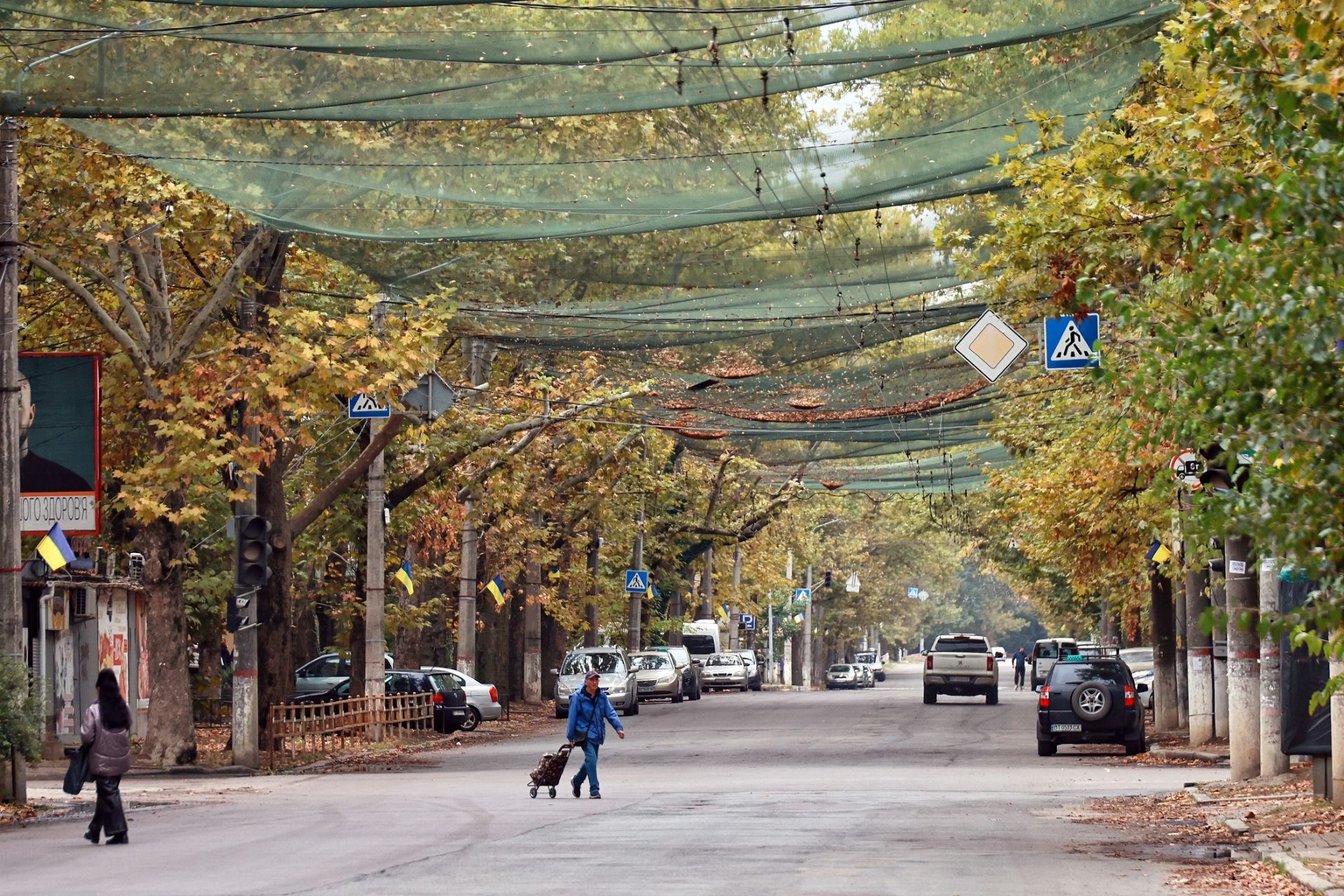 People cross a street protected by anti-drone nets in front-line Kherson, Ukraine, on Oct. 2, 2025. 