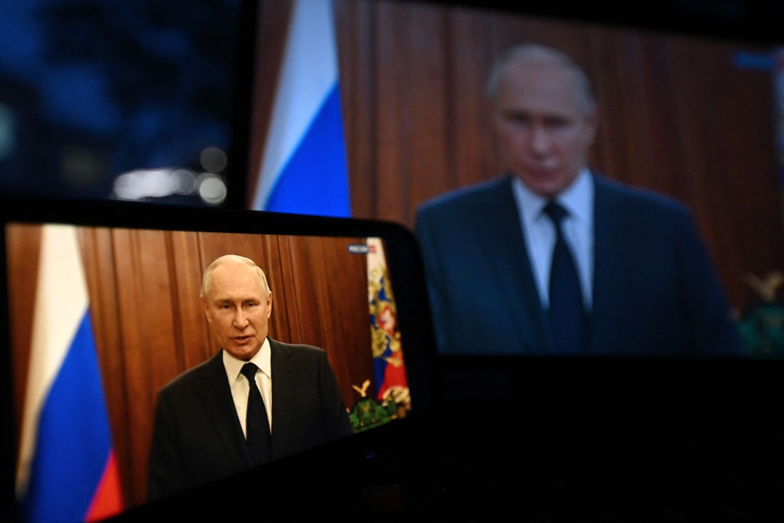 Russian President Vladimir Putin is seen addressing the nation on smartphone and laptop screens in Moscow, Russia, on June 26, 2023. (Natalia Kolesnikova / AFP via Getty Images)