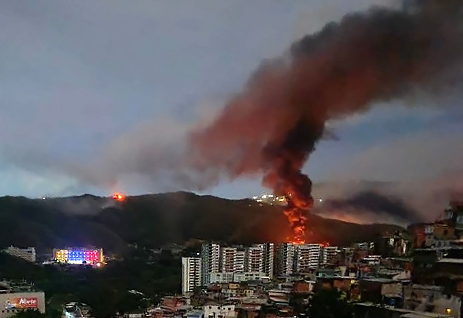 Fire at Fuerte Tiuna, Venezuela’s largest military complex, is seen from a distance after a series of explosions in Caracas, Venezuela, on Jan. 3, 2026.