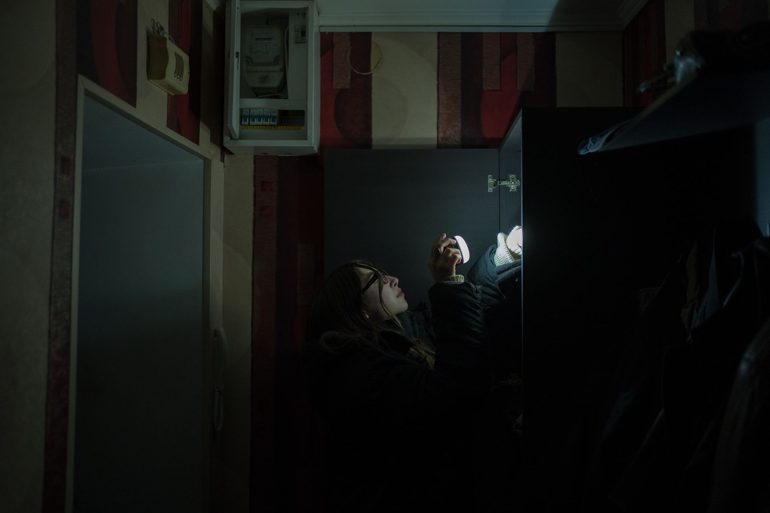 The Kyiv Independent office manager, Olesia Meleshko, looks for clothes in her apartment in Kyiv, Ukraine, on Jan. 14, 2026. 