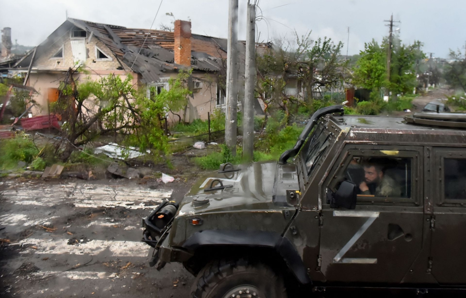 A Russian military vehicle marked with the letter “Z” drives past destroyed houses in Mariupol, Ukraine, on May 18, 2022