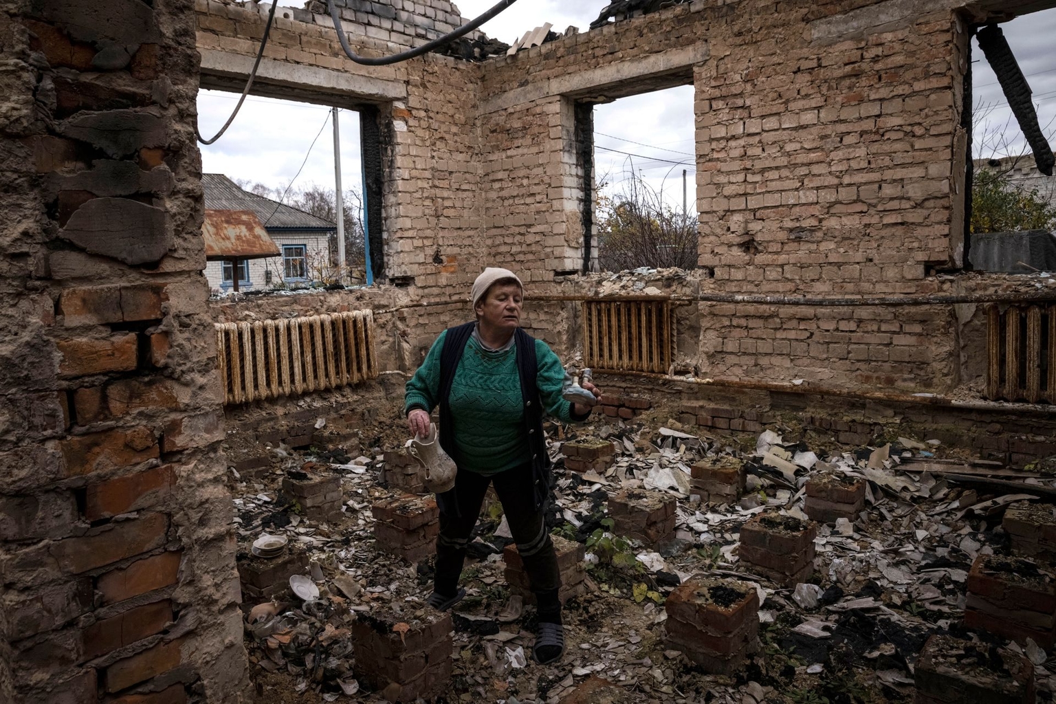 A woman collects ornaments as she walks through her home destroyed during fighting at the start of Russia’s full-scale invasion, in Yahidne village, Chernihiv Oblast, Ukraine, on Oct. 30, 2022.