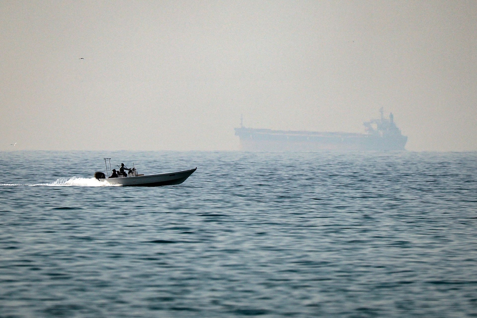 A motorboat cruises along the shore off the town of Al Jeer on the Strait of Hormuz in Ras Al Khaimah, United Arab Emirates, with a tanker seen in the background, on Feb. 25, 2026. 