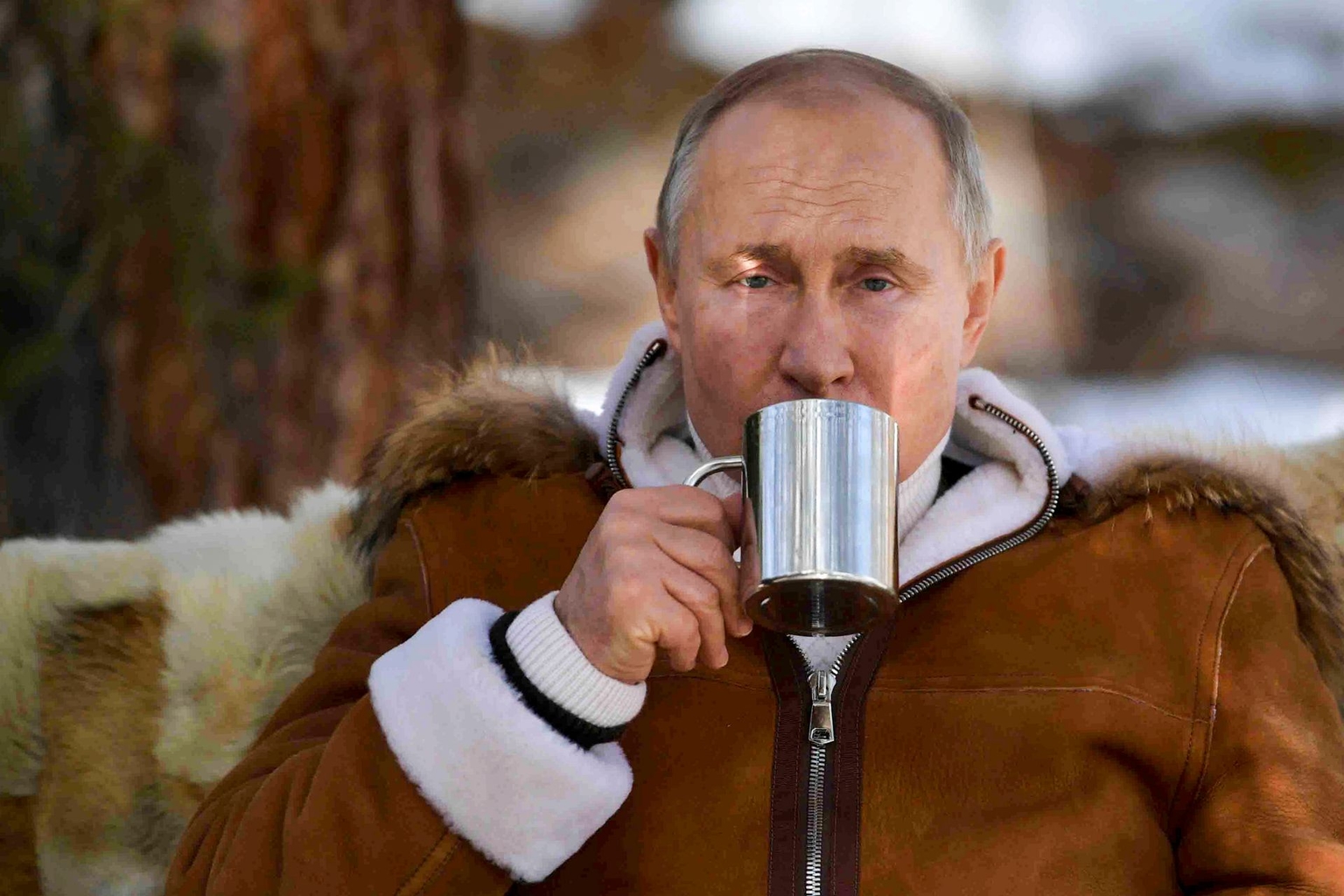Russian President Vladimir Putin drinks during a break in a taiga forest in Siberia, Russia, on March 21, 2021.