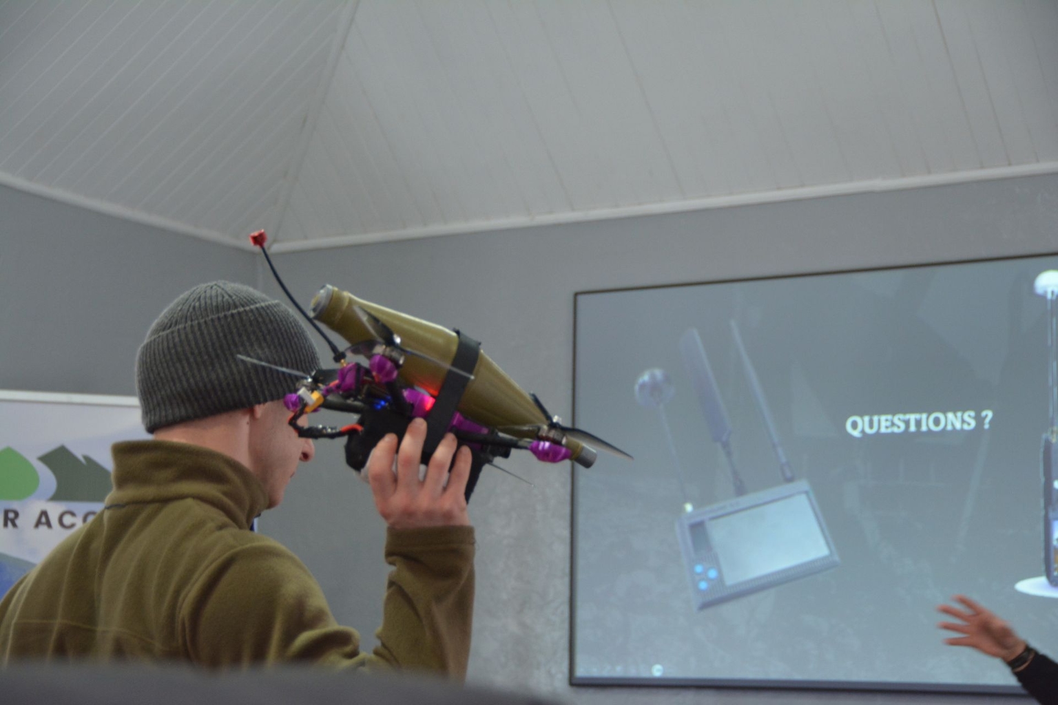 Safer Access trainer Roman Matsiuk holds an FPV drone fitted with a demonstration grenade next to a frequency analyzer screen on Feb. 27, 2026.
