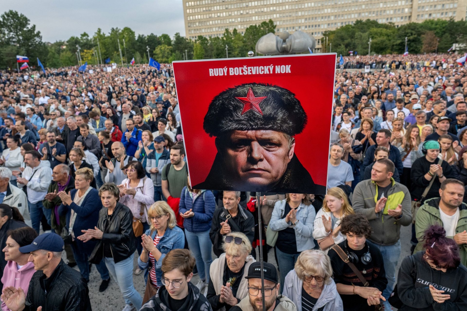 Participants hold a placard depicting Slovak Prime Minister Robert Fico with the text "Enough Red Bolshevik" during a rally in Bratislava, Slovakia, on Sept. 16, 2025.