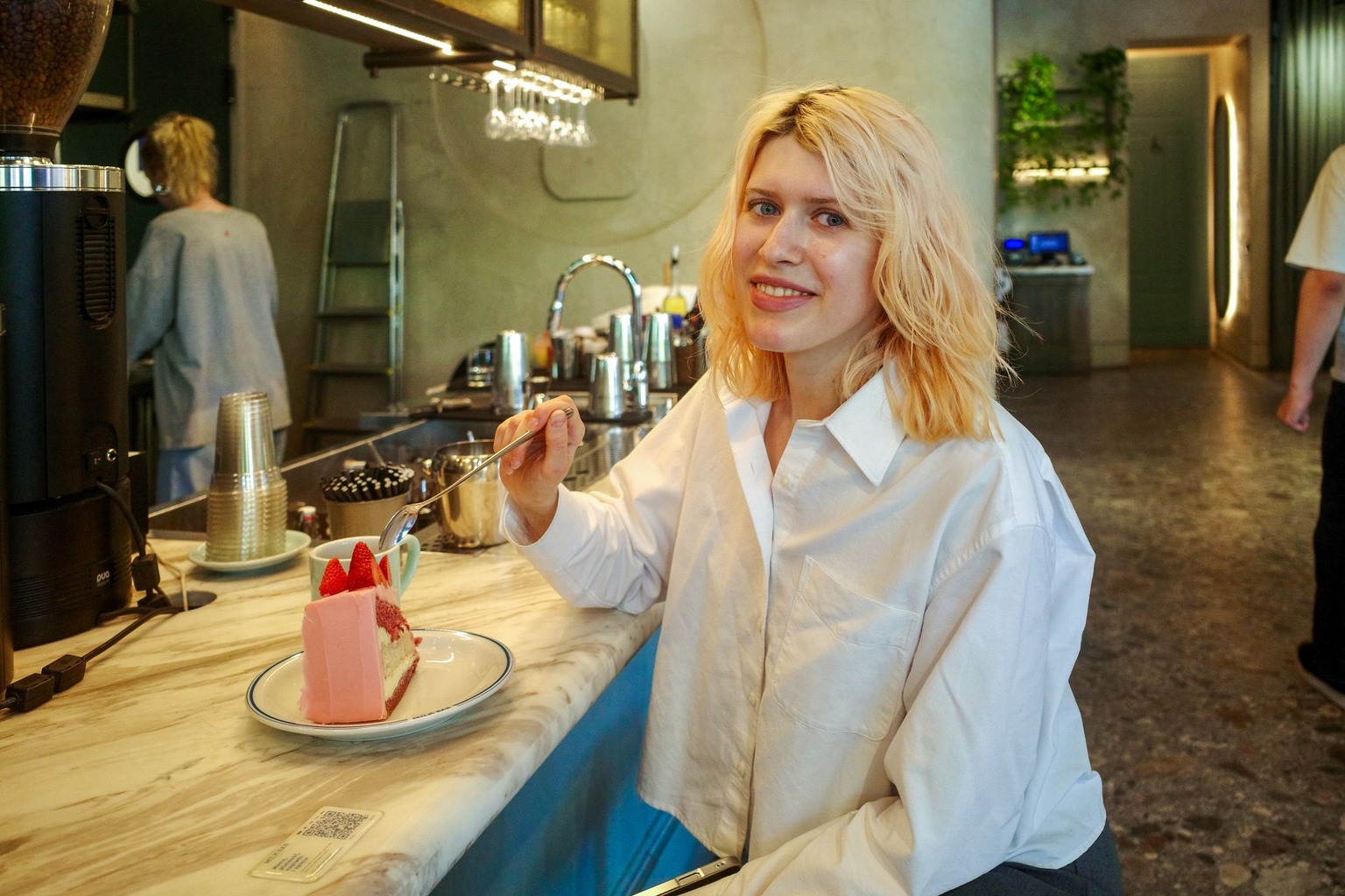 Anastasia Reva, a Ukrainian manager at Milk Bar, sits at the counter and tries one of the cafe's best-selling cakes in Warsaw, Poland, on May 15, 2026. 