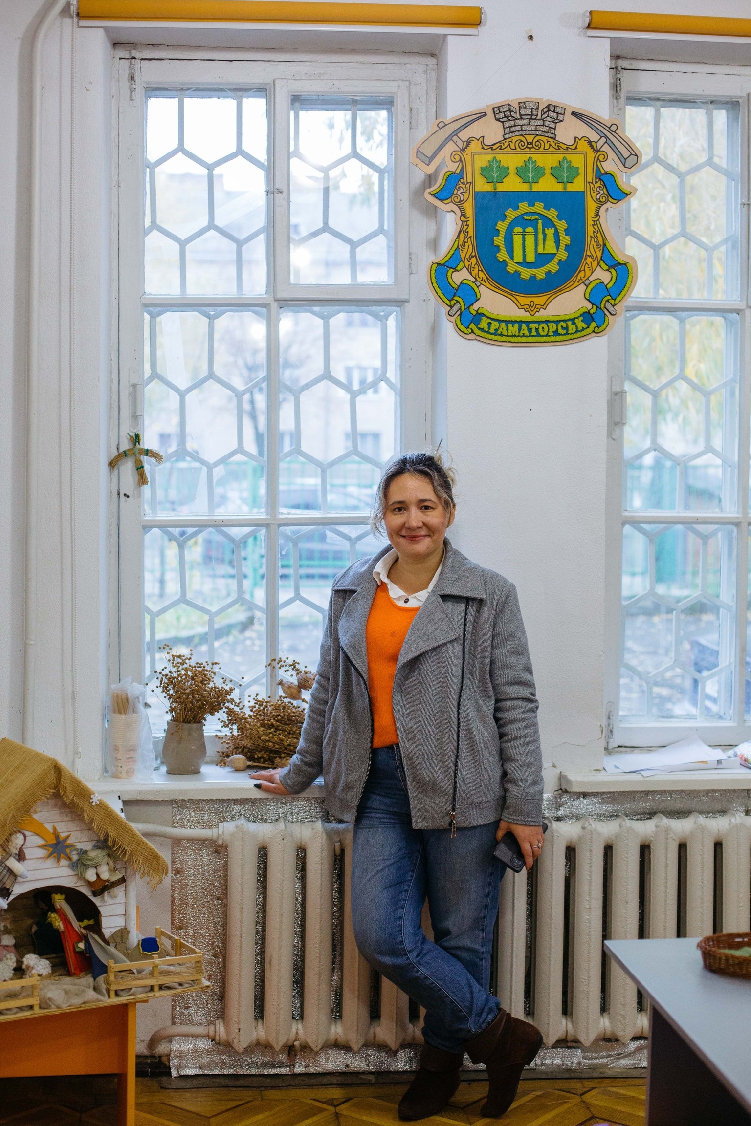 Olha stands beside Kramatorsk’s coat of arms in Lutsk, Volyn Oblast, Ukraine, on Oct. 22, 2026.