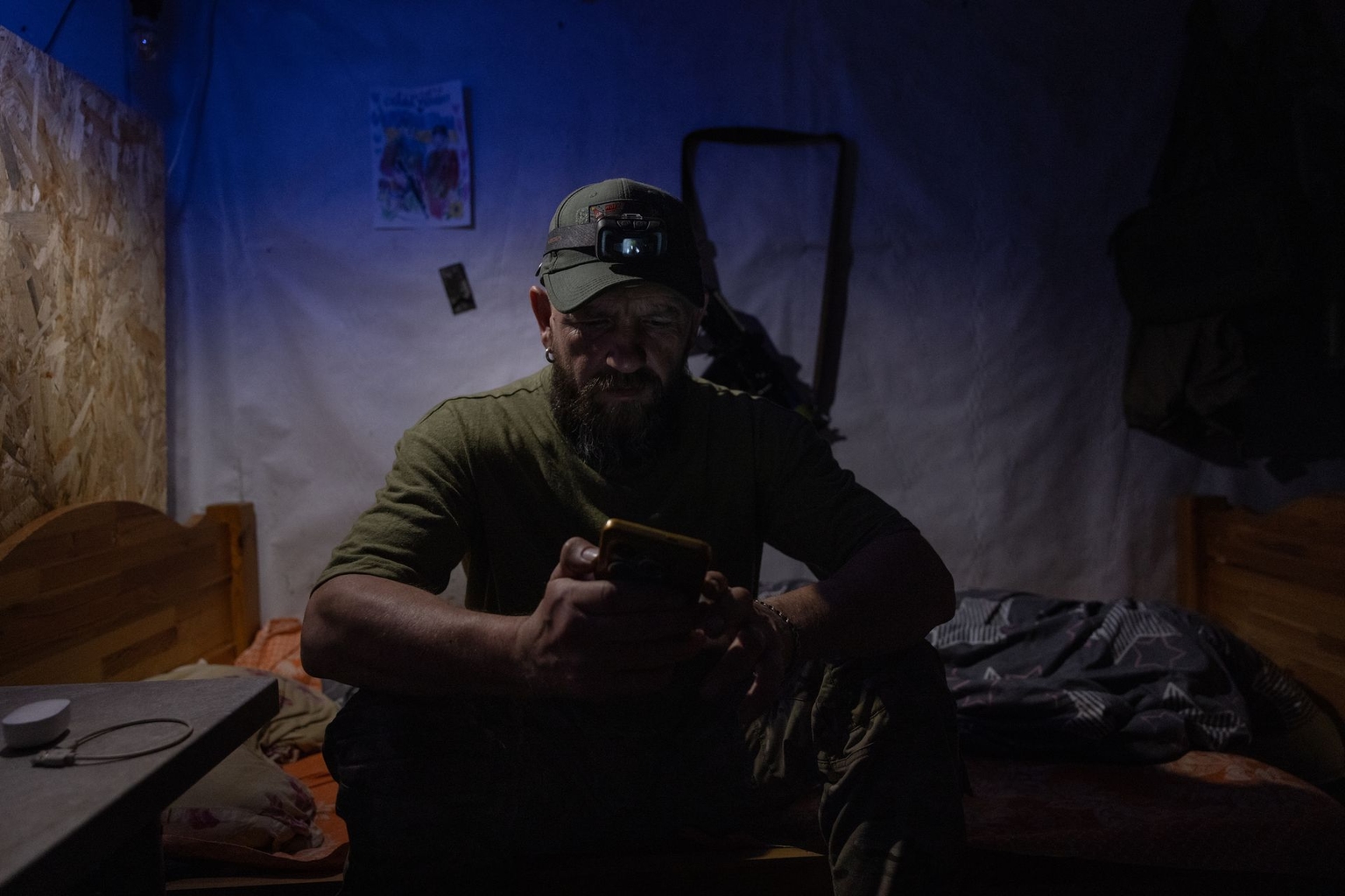 Aibolit sits on his bed in the dugout in the Lyman sector, Ukraine, on Aug. 10, 2026. 