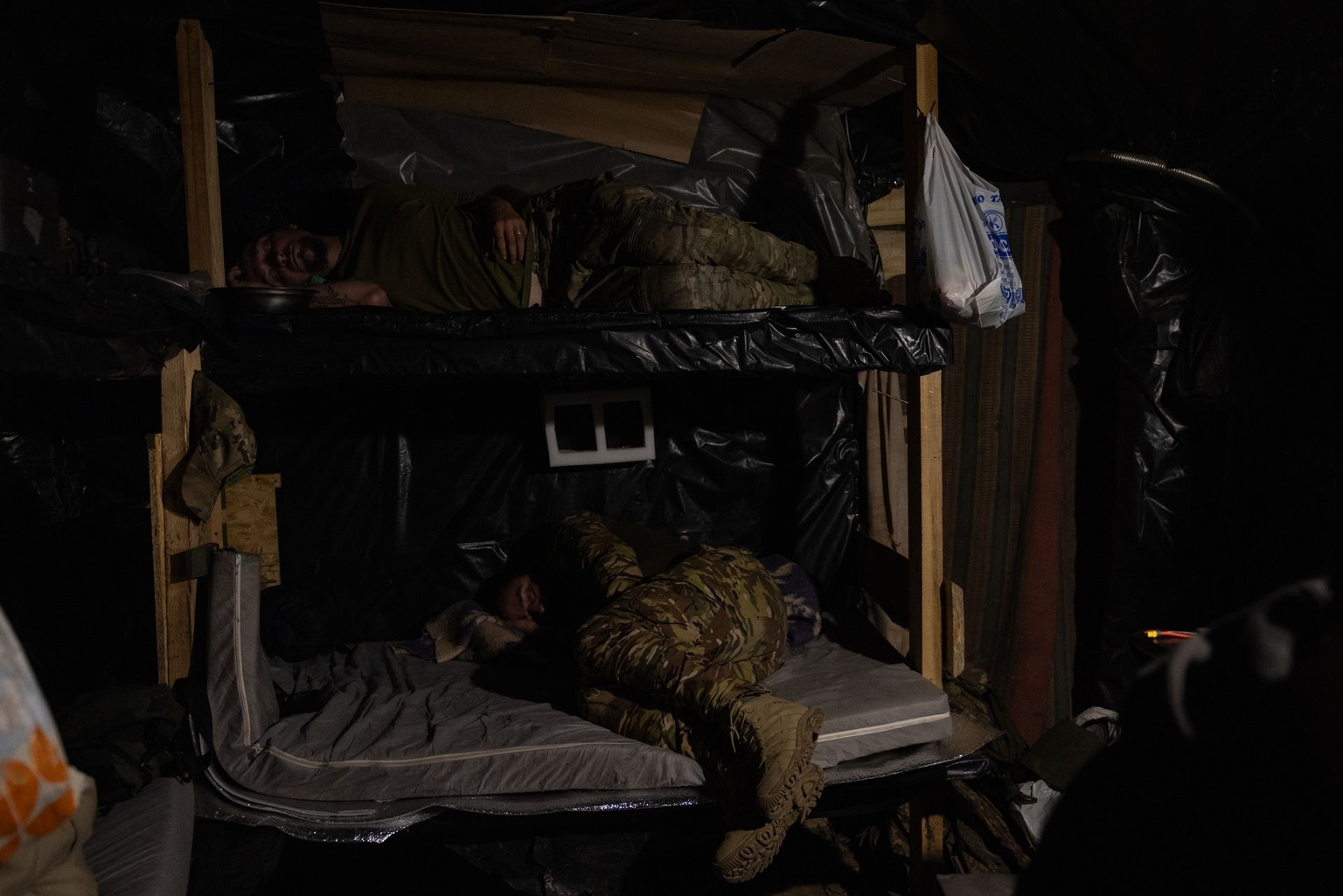 Members of the NAFO crew sleep on the wooden benches in the dugout, in the Lyman sector, Ukraine, on Aug. 11, 2026.