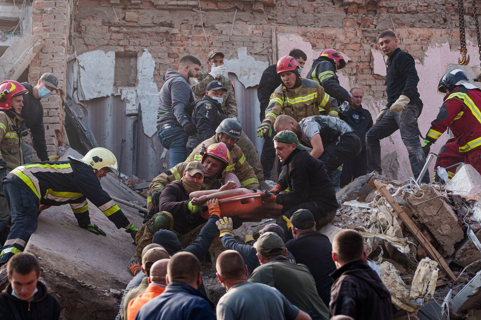 Locals and rescuers carry an injured man from a residential in Pryluky, Chernihiv Oblast, Ukraine, on Oct. 7, 2026.