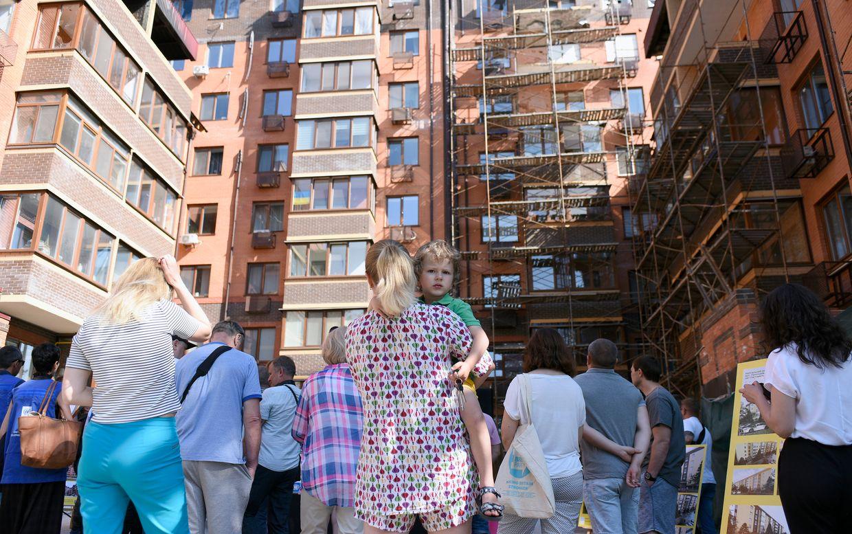 A woman holds a boy during the launch of the rehabilitation process of a multi-story apartment building in Irpin