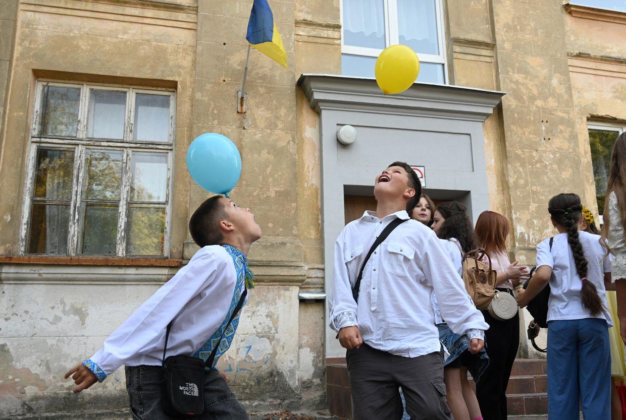 Ukrainian children play in the schoolyard before a bell ceremony on the first day of the new school year in Lviv