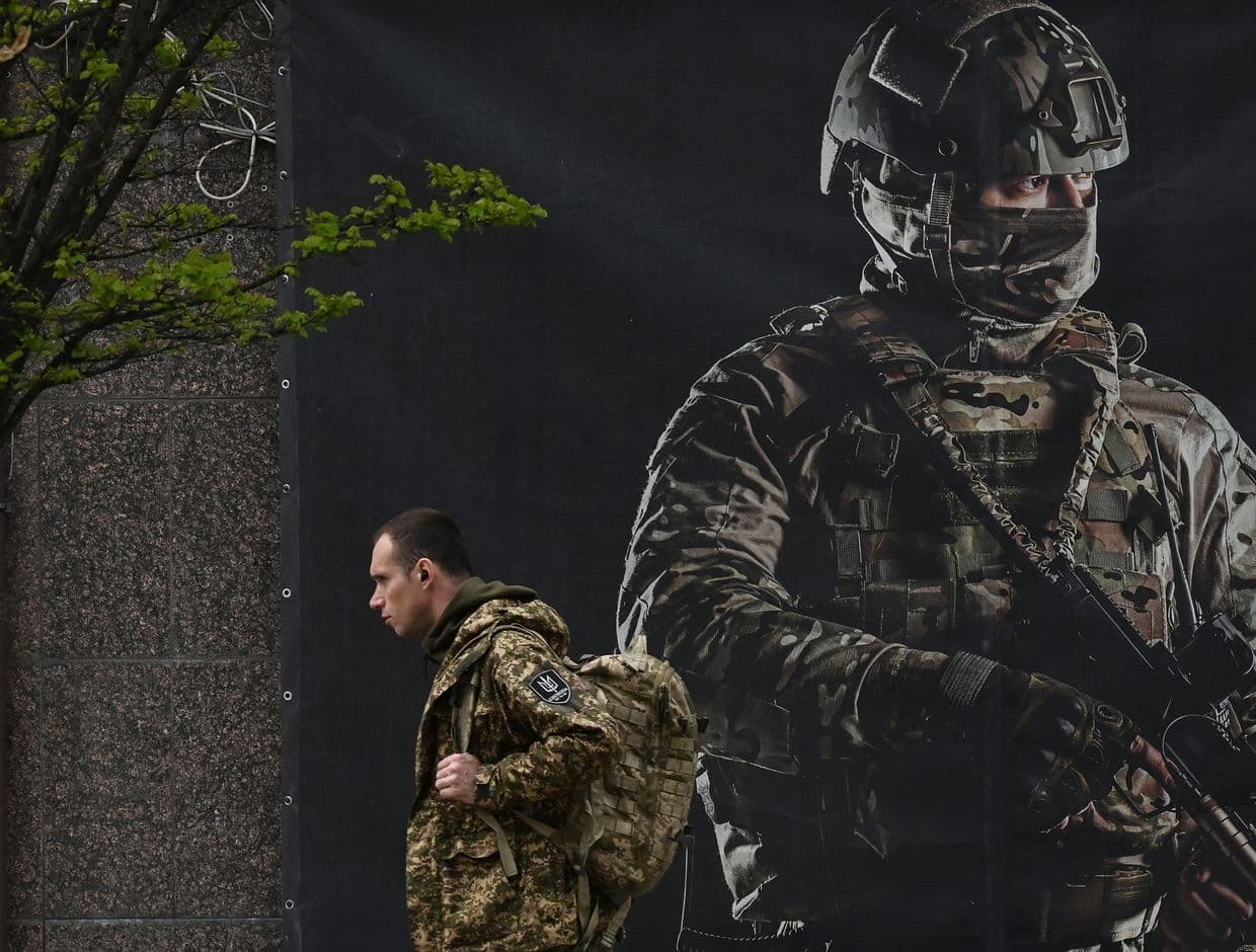  A Ukrainian serviceman passes a recruiting poster in Kyiv, Ukraine, on April 23, 2024