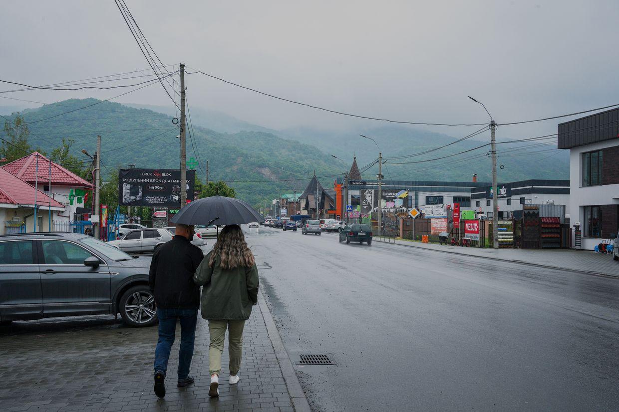 Two people walk down the street in Vynohradiv, Zakarpattia Oblast, Ukraine on May 22, 2025. 