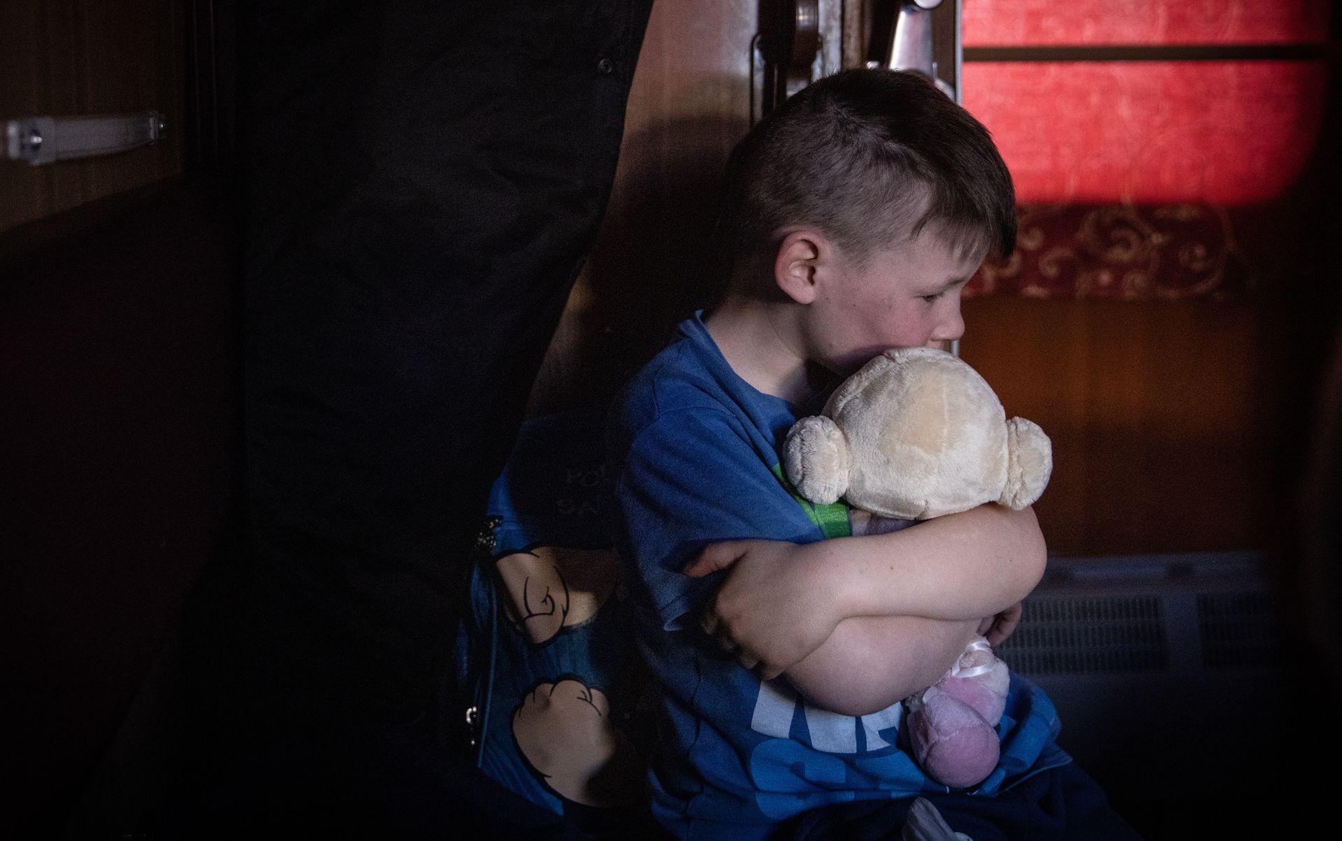 A boy on a train hugs a soft toy during an evacuation from Polohy, Zaporizhzhia Oblast to western Ukraine on March 26, 2022
