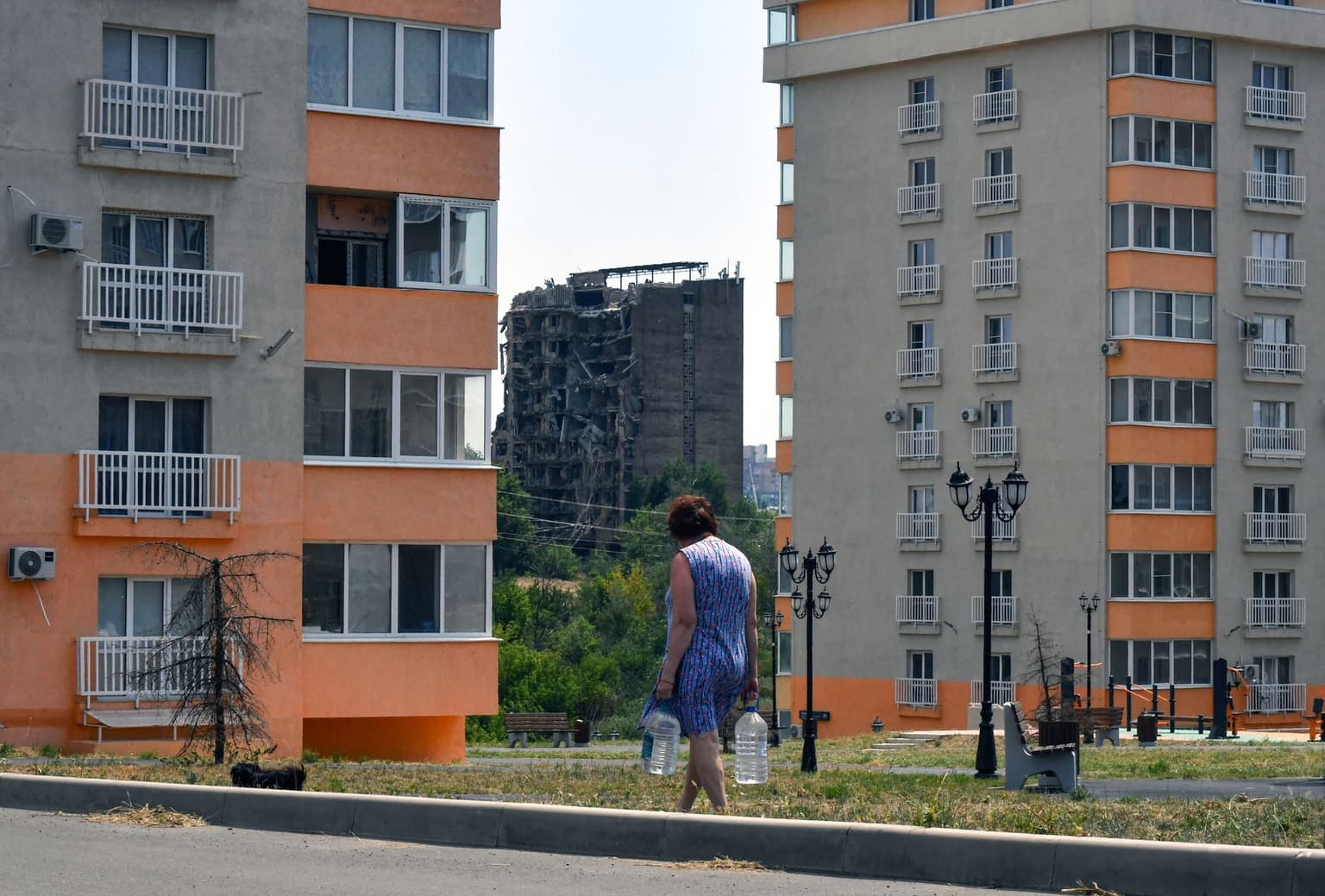 A woman carries bottles of water in the Russia-occupied Mariupol, Ukraine, on July 14, 2025.
