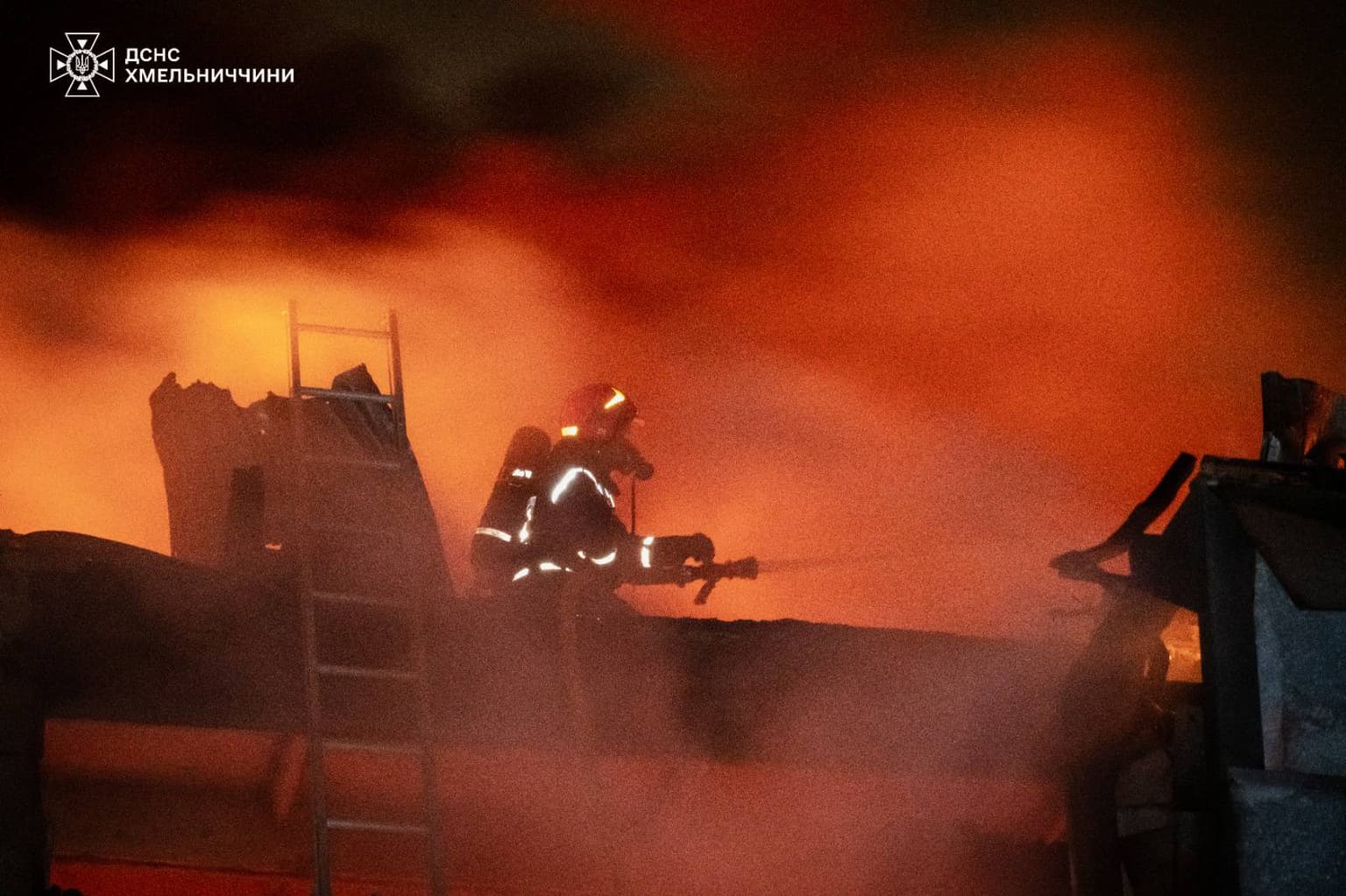 A firefighter surrounded in an orangehaze puts out a fire