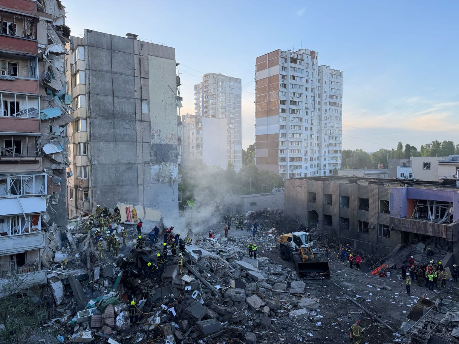 First responders stand atop a pile of rubble searching for people trapped underneath.