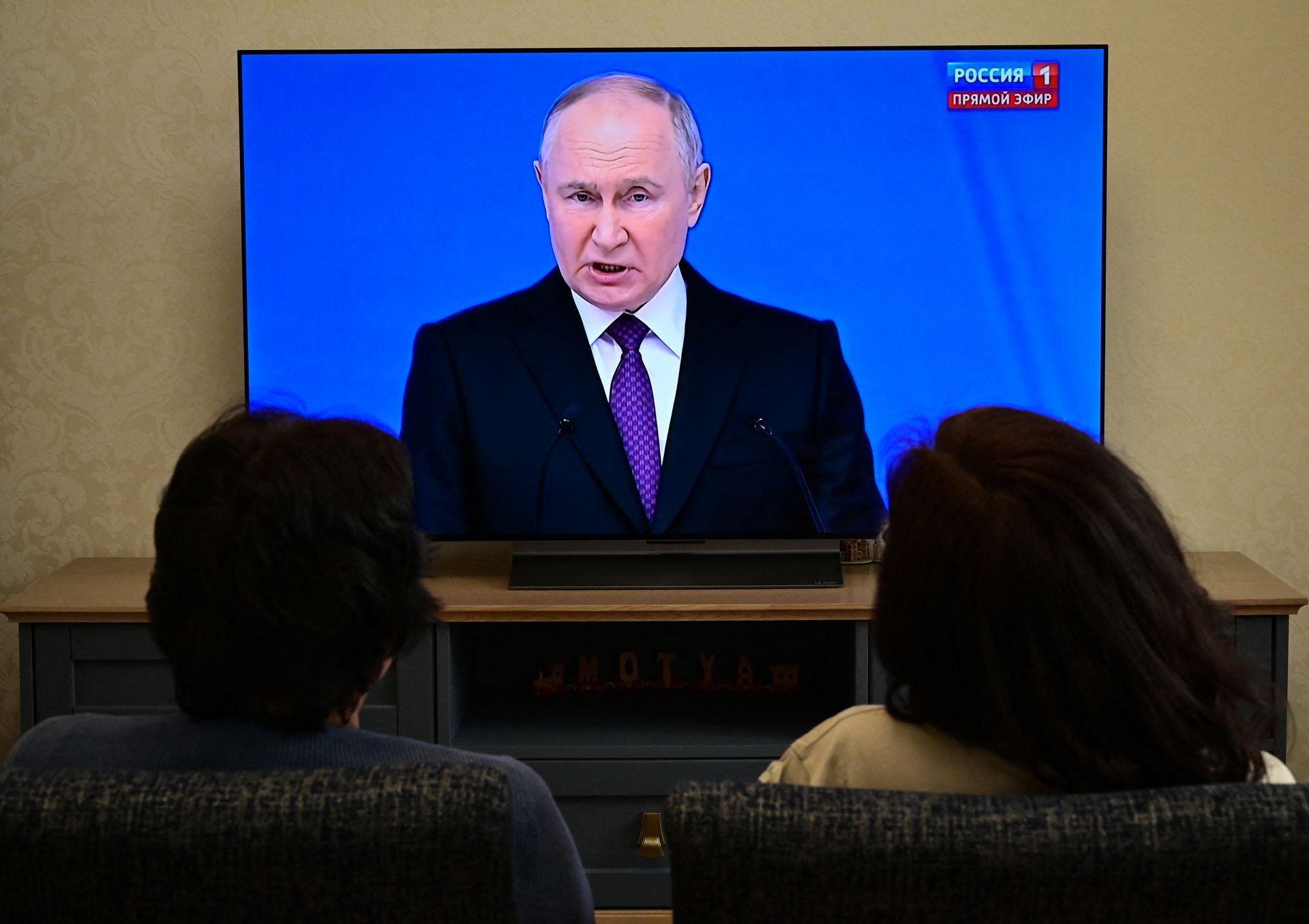A family watches a TV broadcast of Russian President Vladimir Putin in Moscow, Russia, on Feb. 29, 2024.
