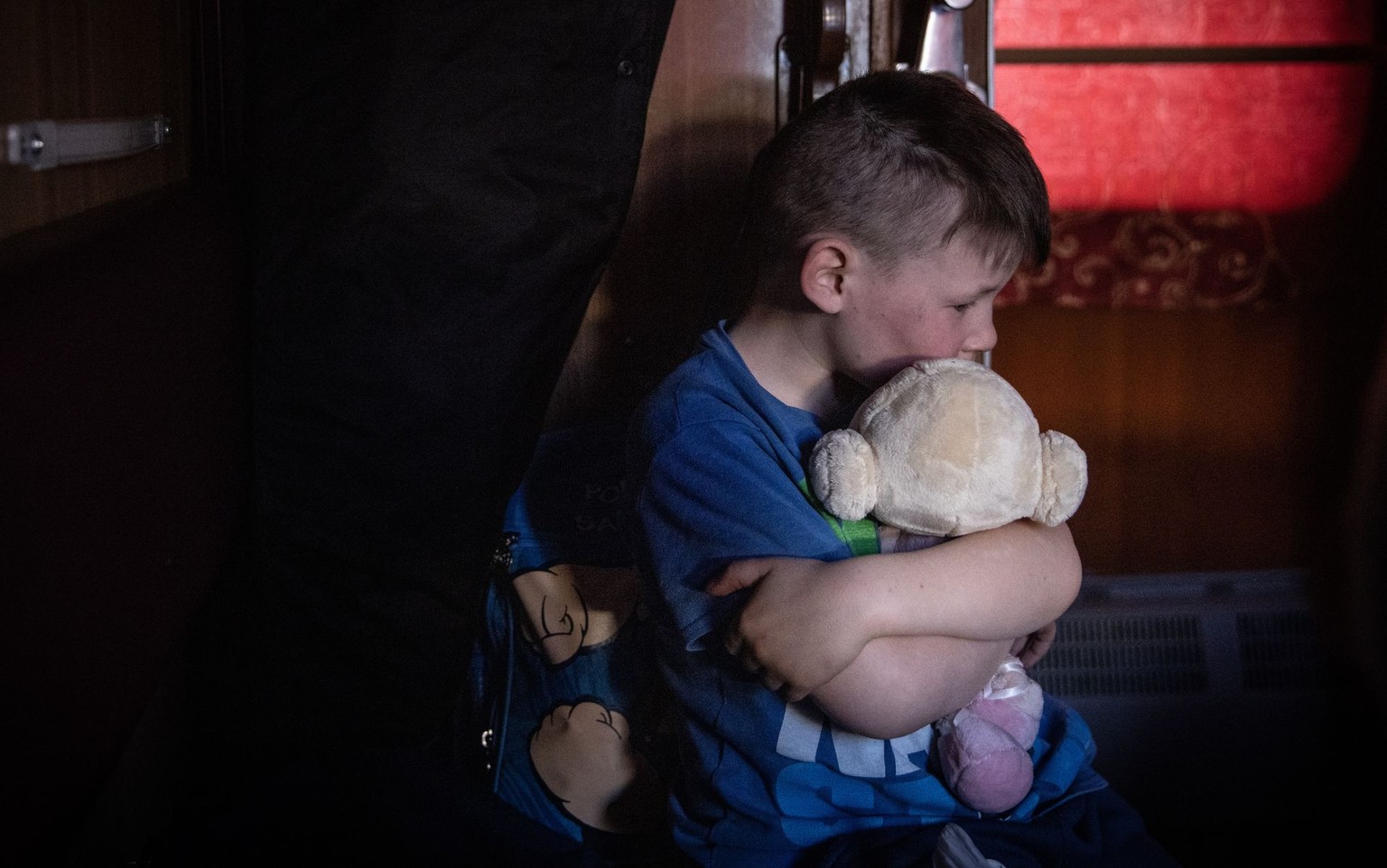 A boy on a train hugs a soft toy during an evacuation from Polohy, Zaporizhzhia Oblast to western Ukraine on March 26, 2022