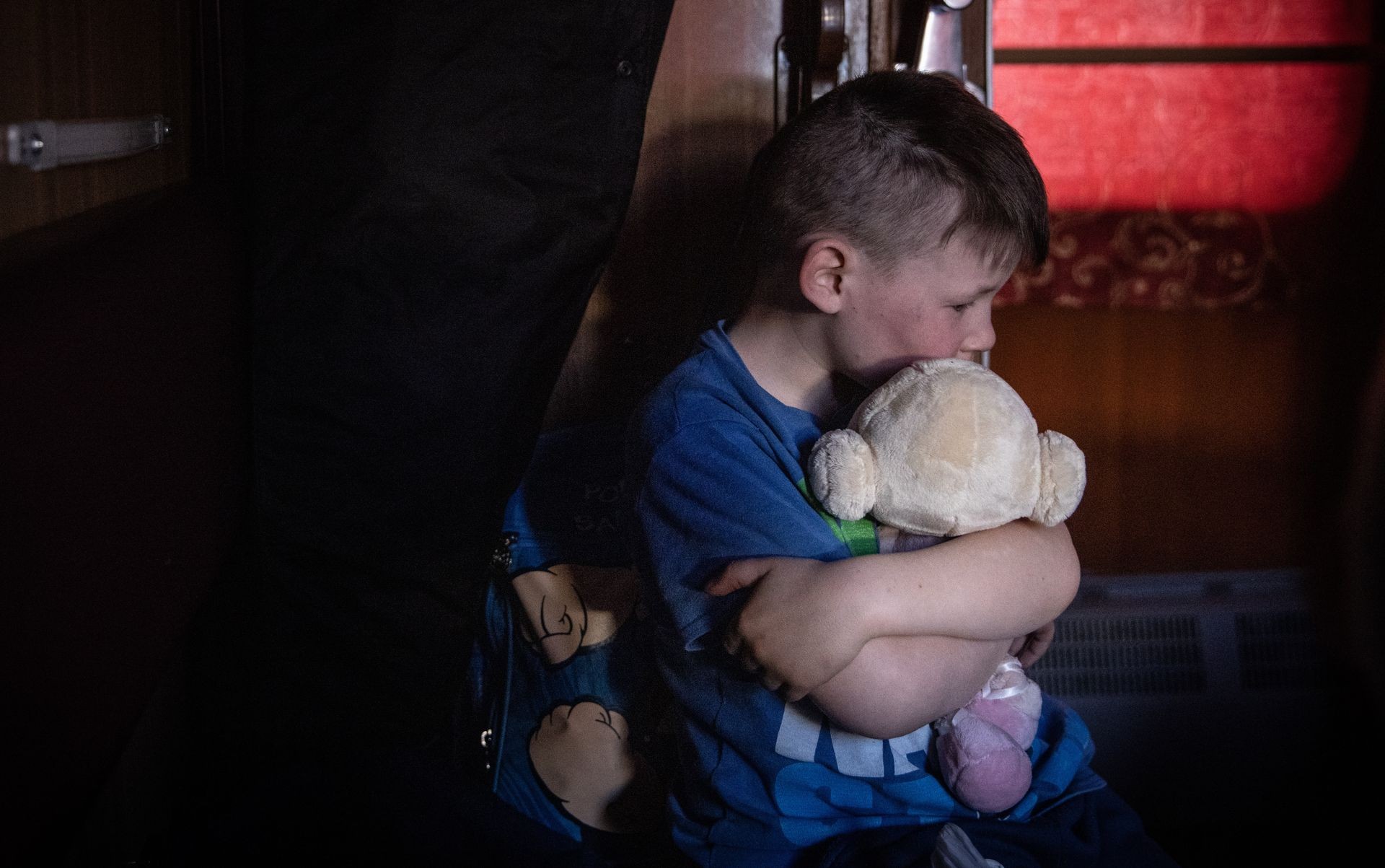 A boy on a train hugs a soft toy during an evacuation from Polohy, Zaporizhzhia Oblast to western Ukraine on March 26, 2022